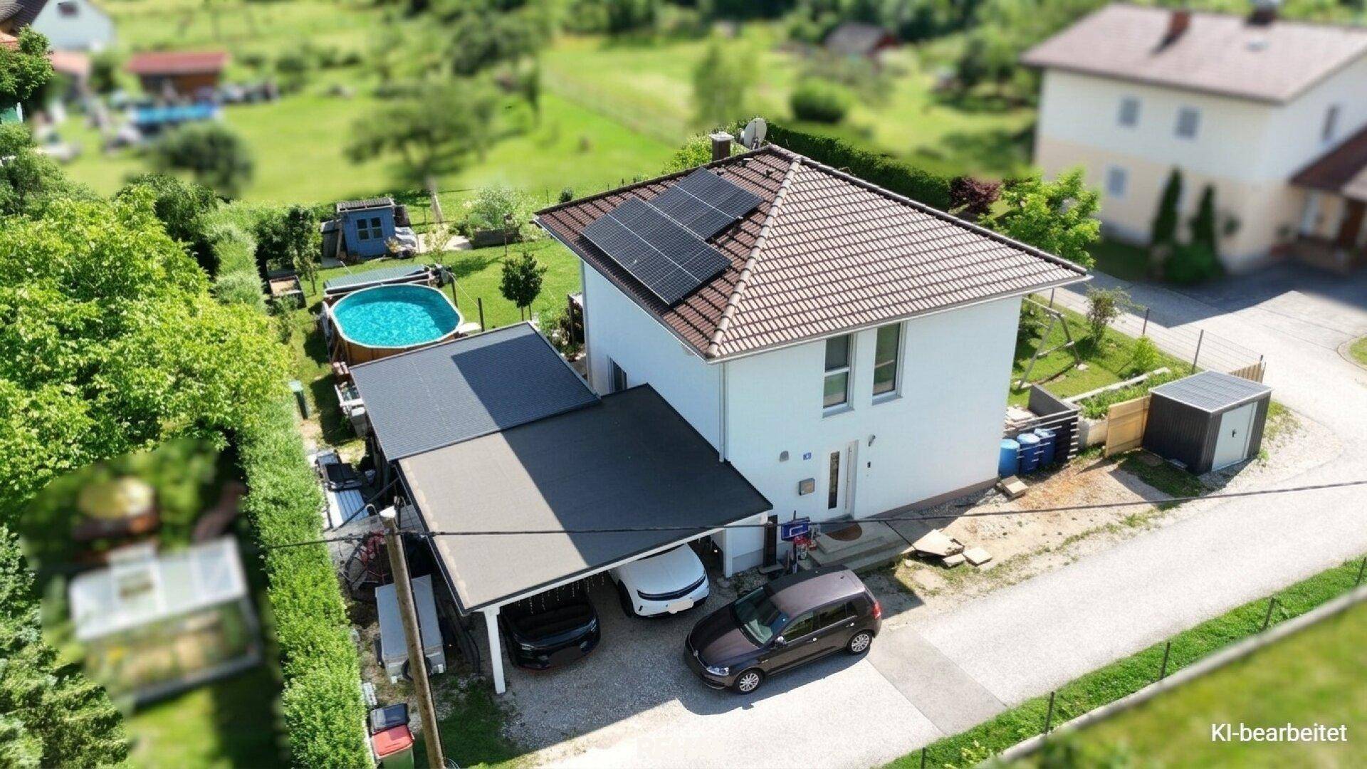 Vogelperspektive des Hauses mit Carport, Einfahrt und einem Pool im hinteren Gartenbereich.