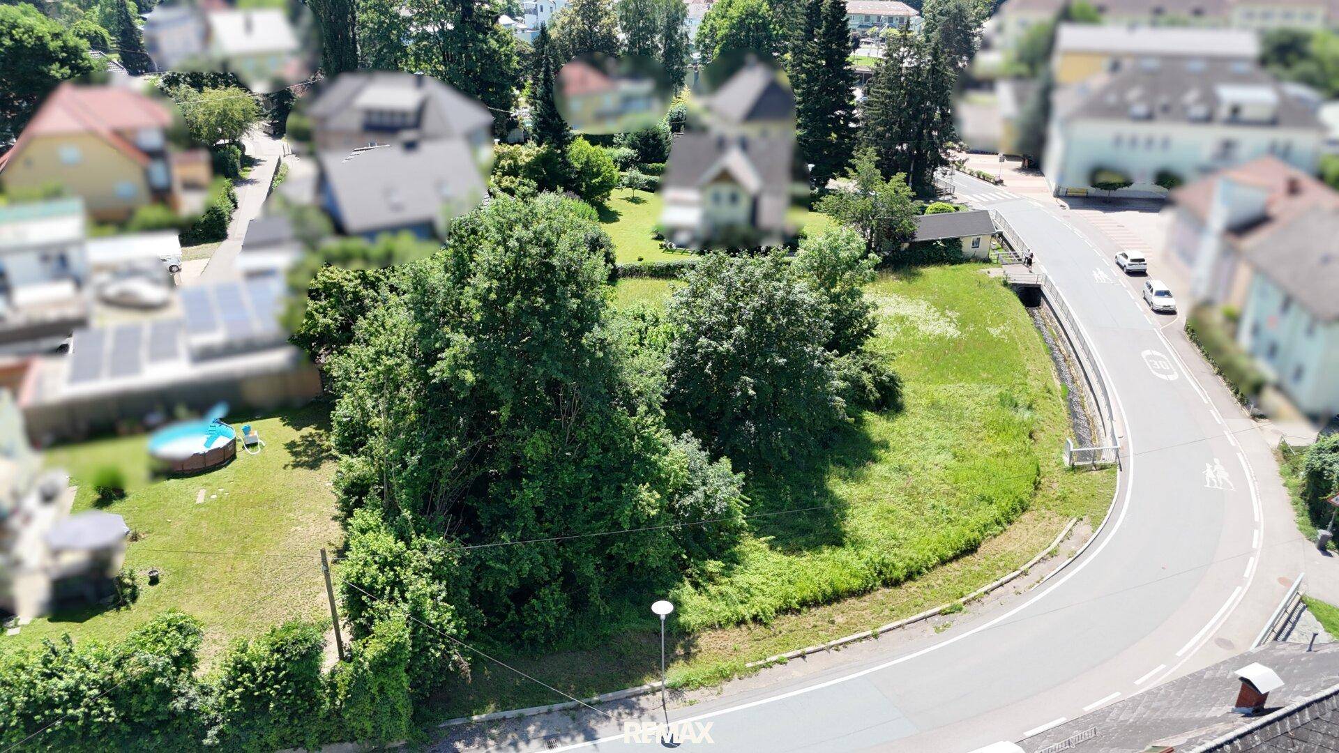 Weitläufige Luftaufnahme eines unbebauten Grundstücks mit angrenzender Straße und Blick auf die Nachbarschaft.