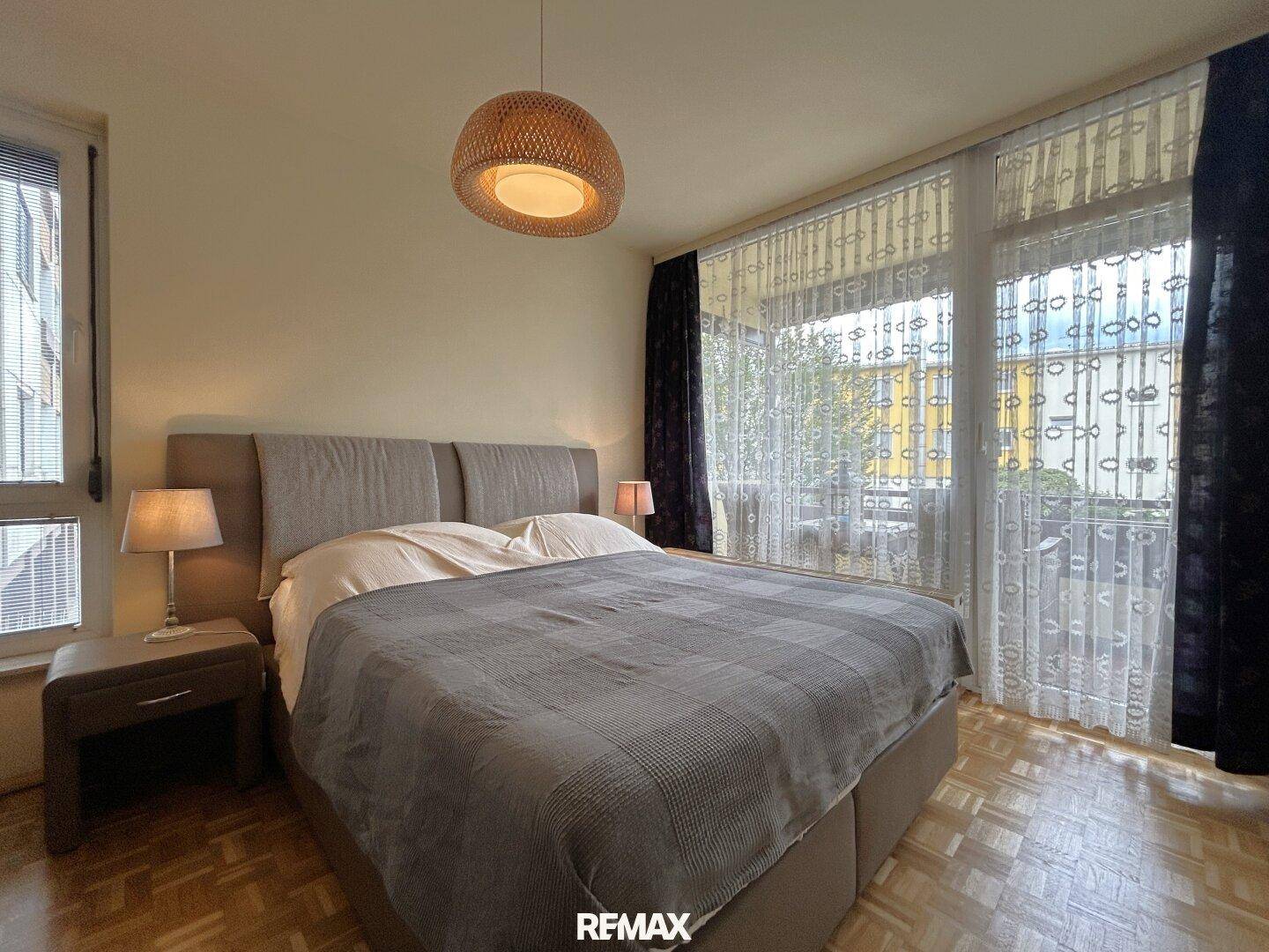 Helles Schlafzimmer mit Doppelbett, Parkettboden und direktem Zugang zum Balkon.