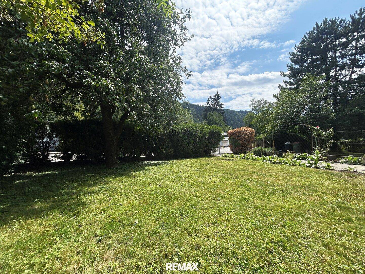 Gepflegter Garten mit Hecke und weitem Blick auf die umliegende Hügellandschaft.