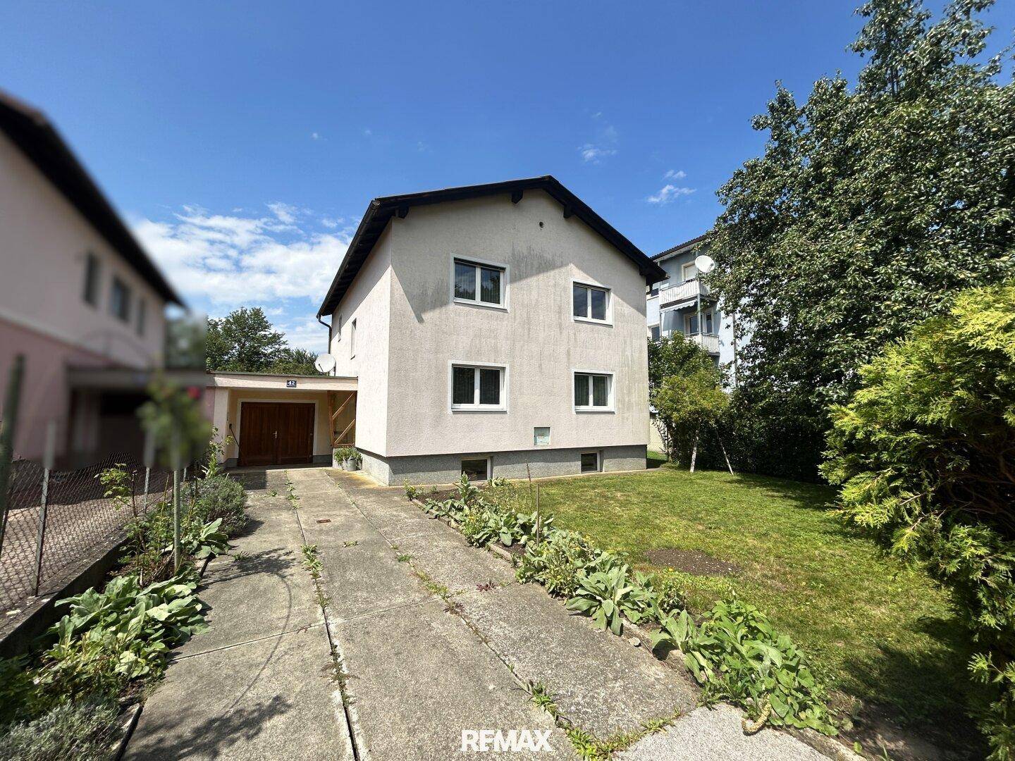 Vorderansicht des Einfamilienhauses mit Vorgarten und Zufahrt an einem sonnigen Tag.