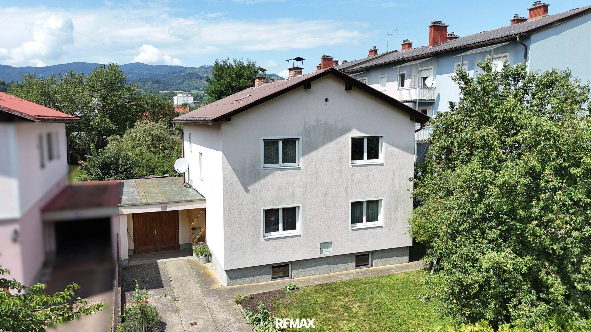 Übersicht des Einfamilienhauses mit angrenzenden Gebäuden und grüner Umgebung.