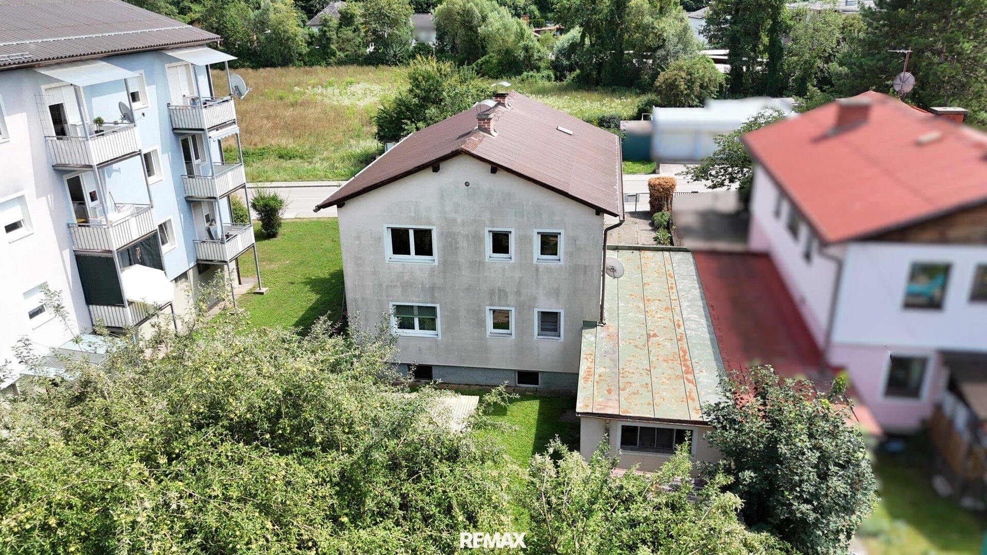 Luftaufnahme des Hinterhofs mit Garten und angrenzenden Gebäuden in grüner Umgebung.