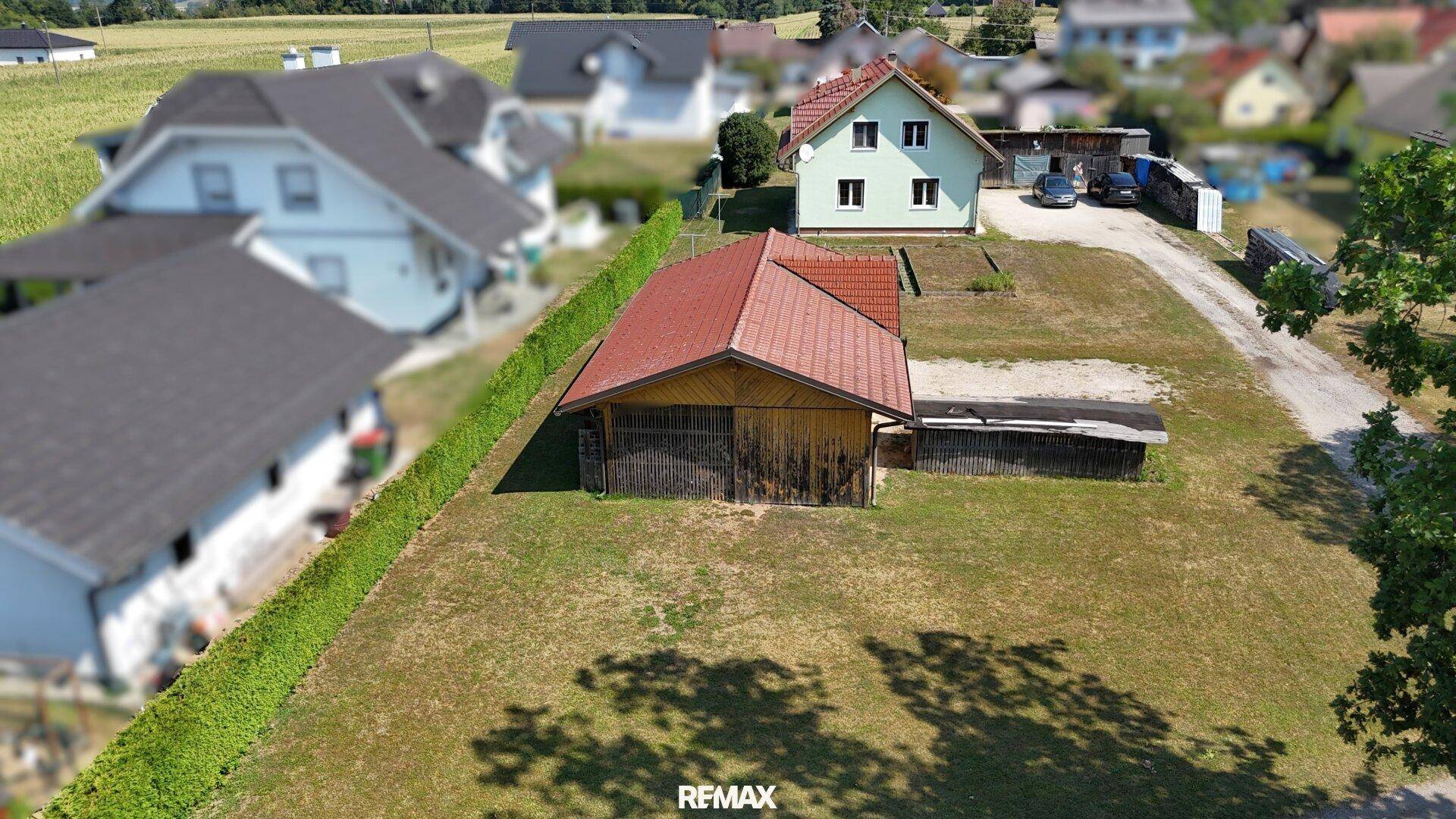Weitläufige Luftaufnahme des Grundstücks mit Wohnhaus und Nebengebäude, umgeben von grüner Landschaft.