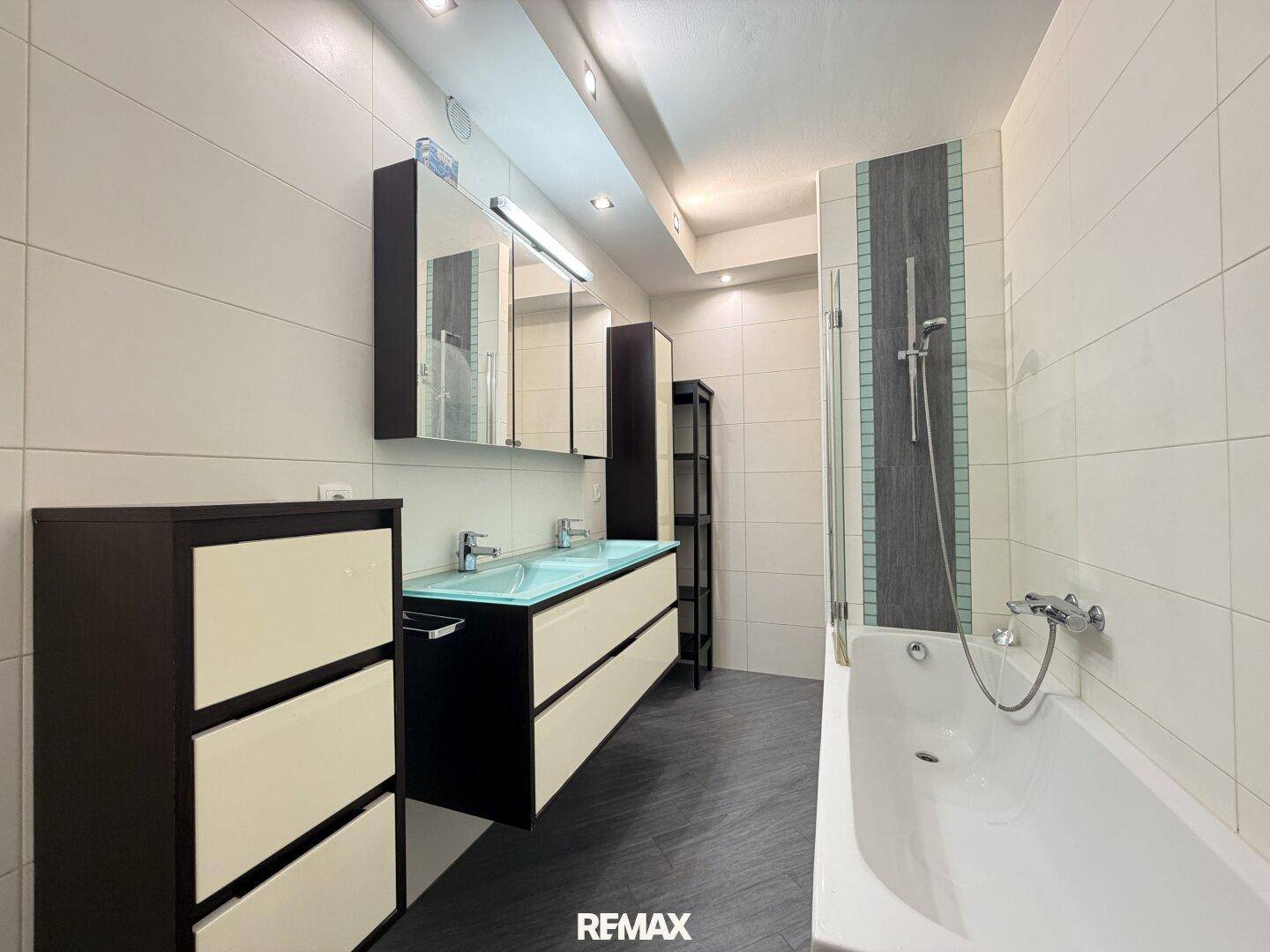 Modernes Badezimmer mit Doppelwaschbecken, Badewanne und weißen Wandfliesen.