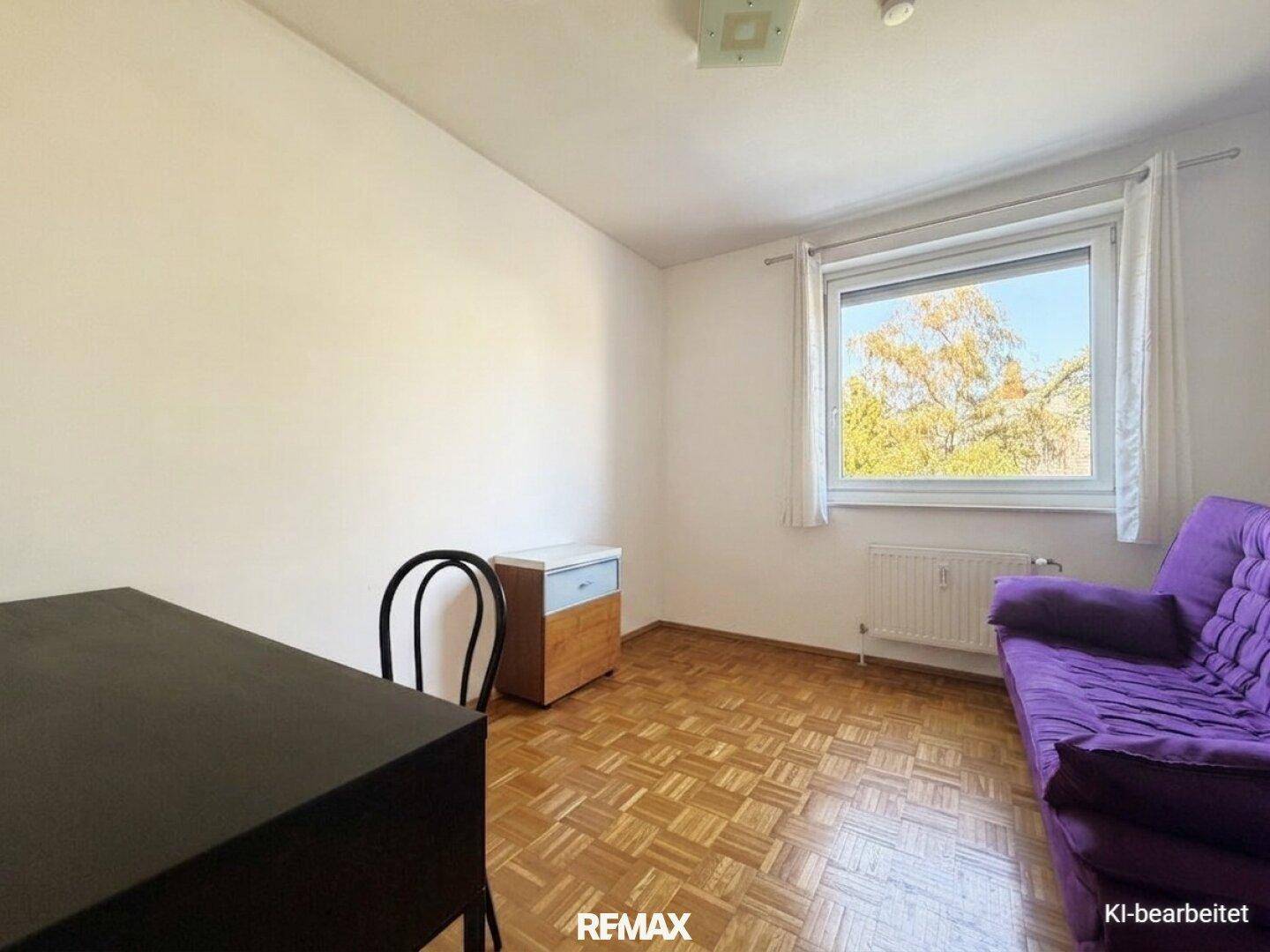 Helles Zimmer mit Parkettboden, lila Sofa und Fenster mit Blick ins Grüne.
