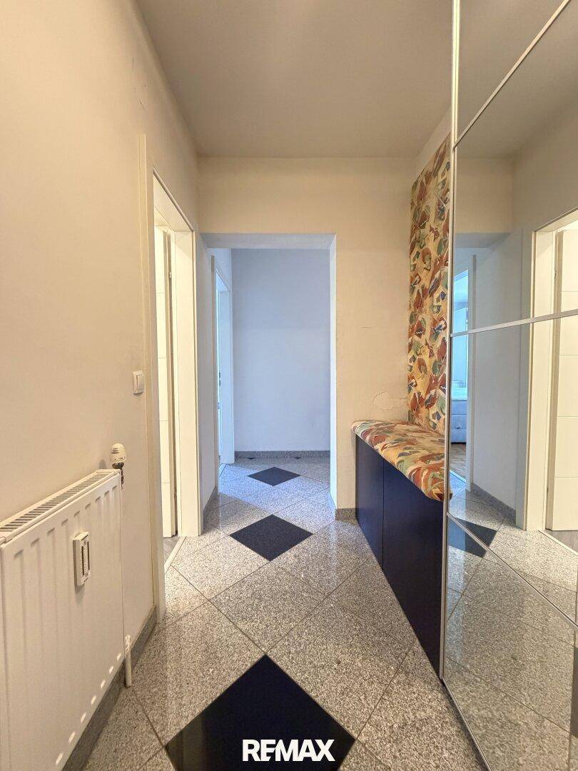 Flur mit Fliesenboden und Spiegelschrank, führt zu weiteren Räumen.