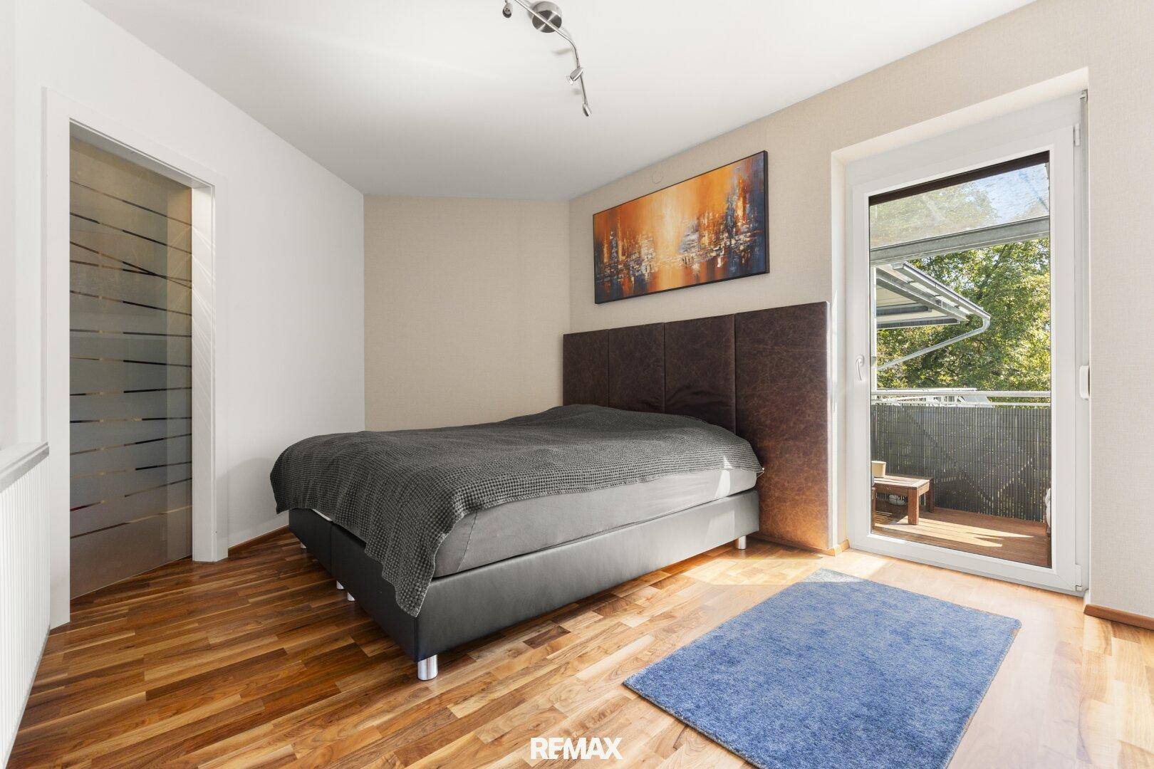 Gemütliches Schlafzimmer mit Holzboden und direktem Zugang zum sonnigen Balkon.