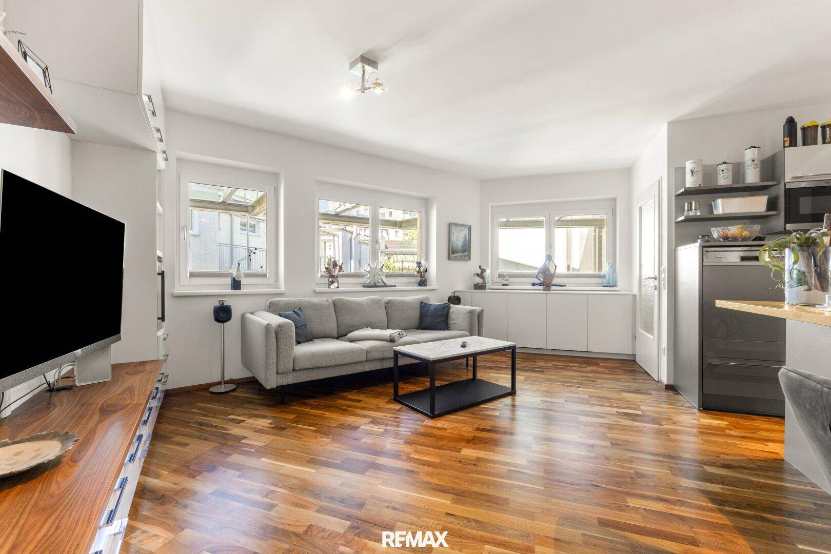 Helles Wohnzimmer mit bequemer Couch, modernem Couchtisch und großen Fenstern mit Holzboden.