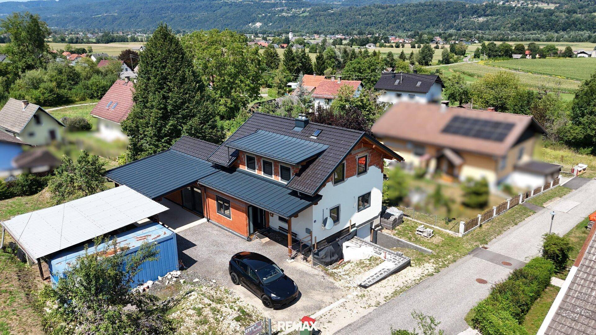 Vogelperspektive des Hauses mit Zufahrt, Parkplatz und angrenzendem Gartenbereich.