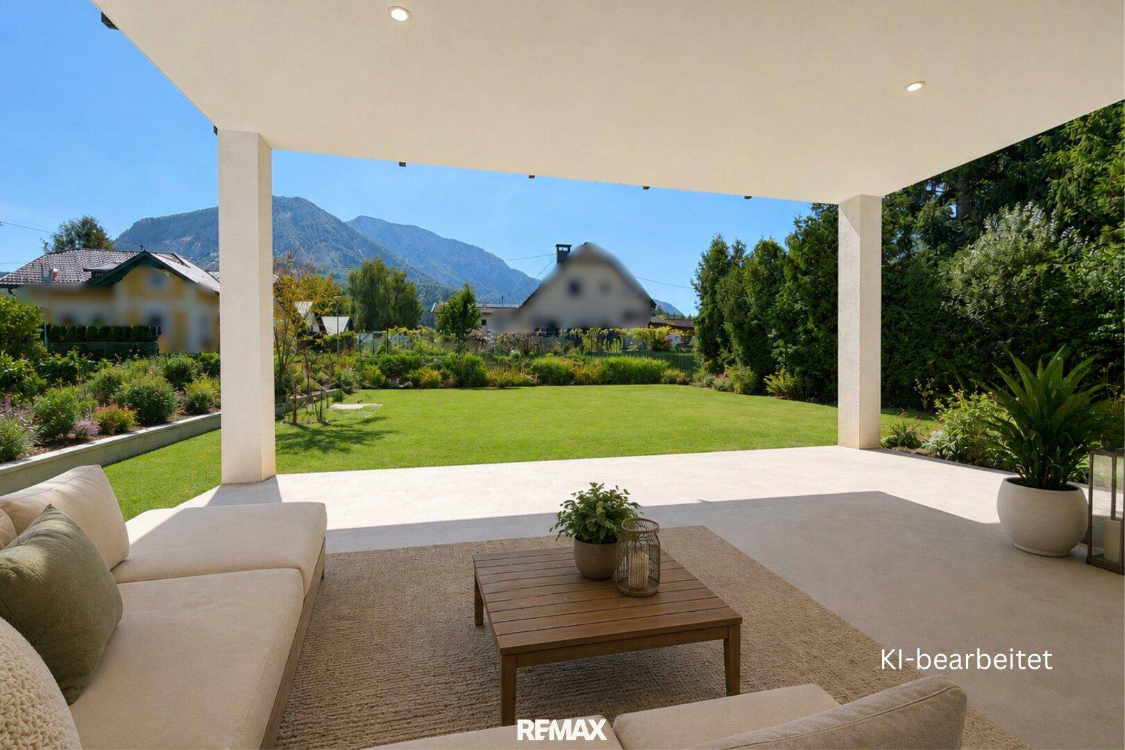 Überdachte Terrasse mit bequemen Sitzmöbeln, Blick auf den Garten und die Berge.
