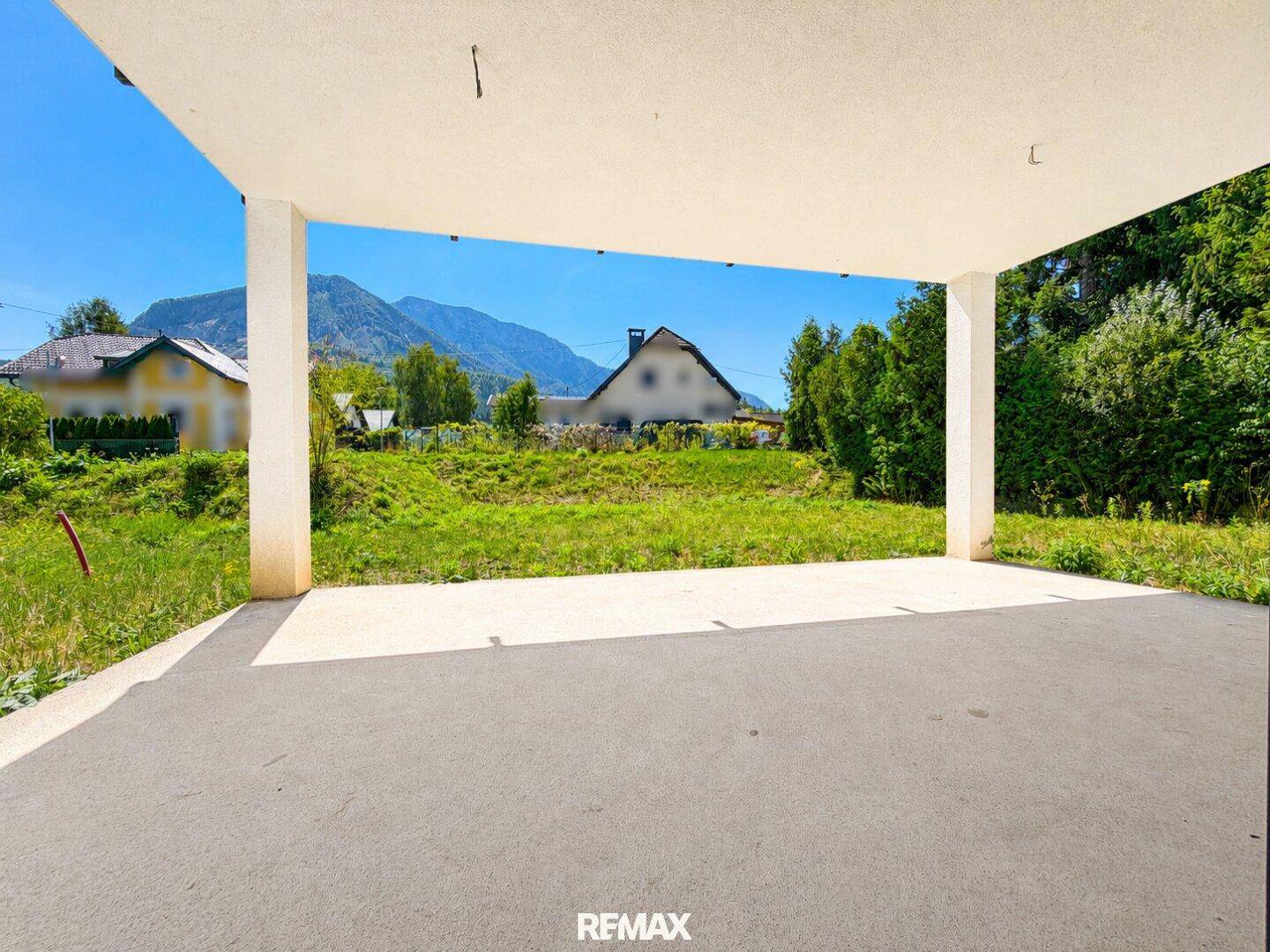 Geräumige, überdachte Terrasse mit weitem Blick auf den Garten und die umliegenden Berge.