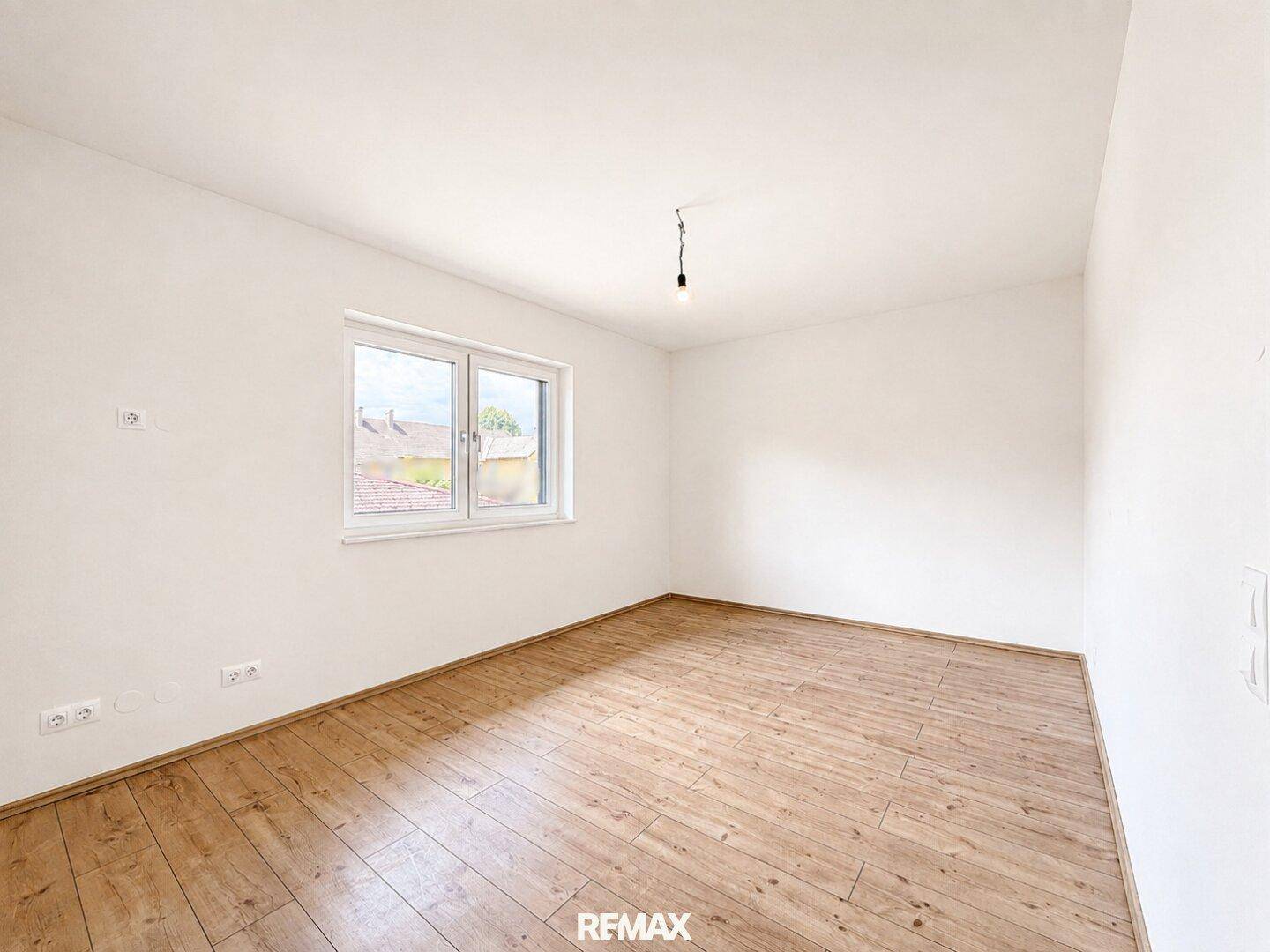 Leeres Zimmer mit Holzboden und einem Fenster, ideal als Schlaf- oder Kinderzimmer.