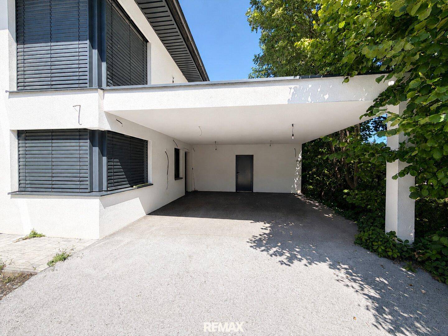 Überdachter Carport-Bereich des Hauses mit direktem Zugang zum Eingang.