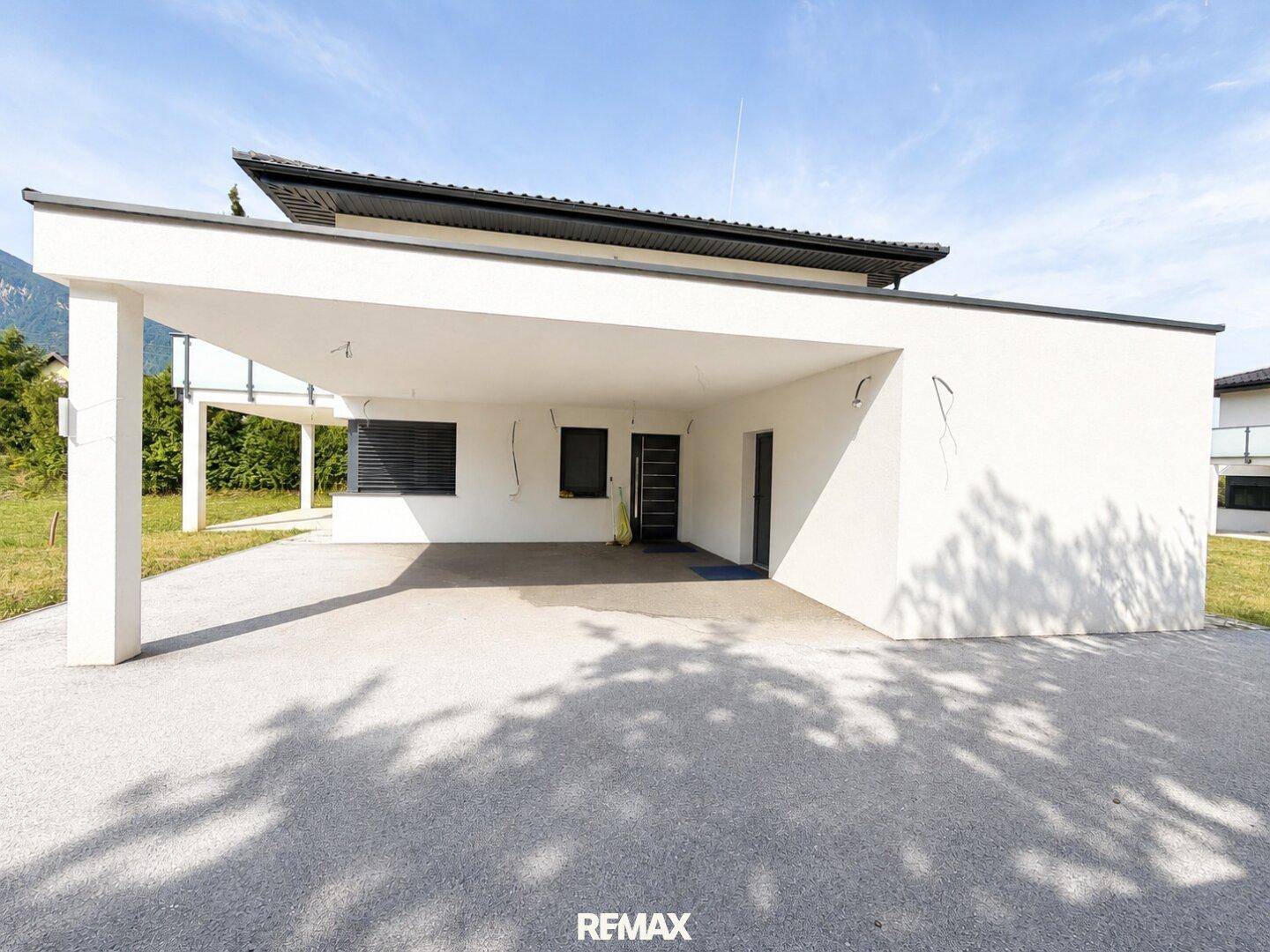 Vorderansicht des modernen Hauses mit integriertem Carport und Zufahrt.