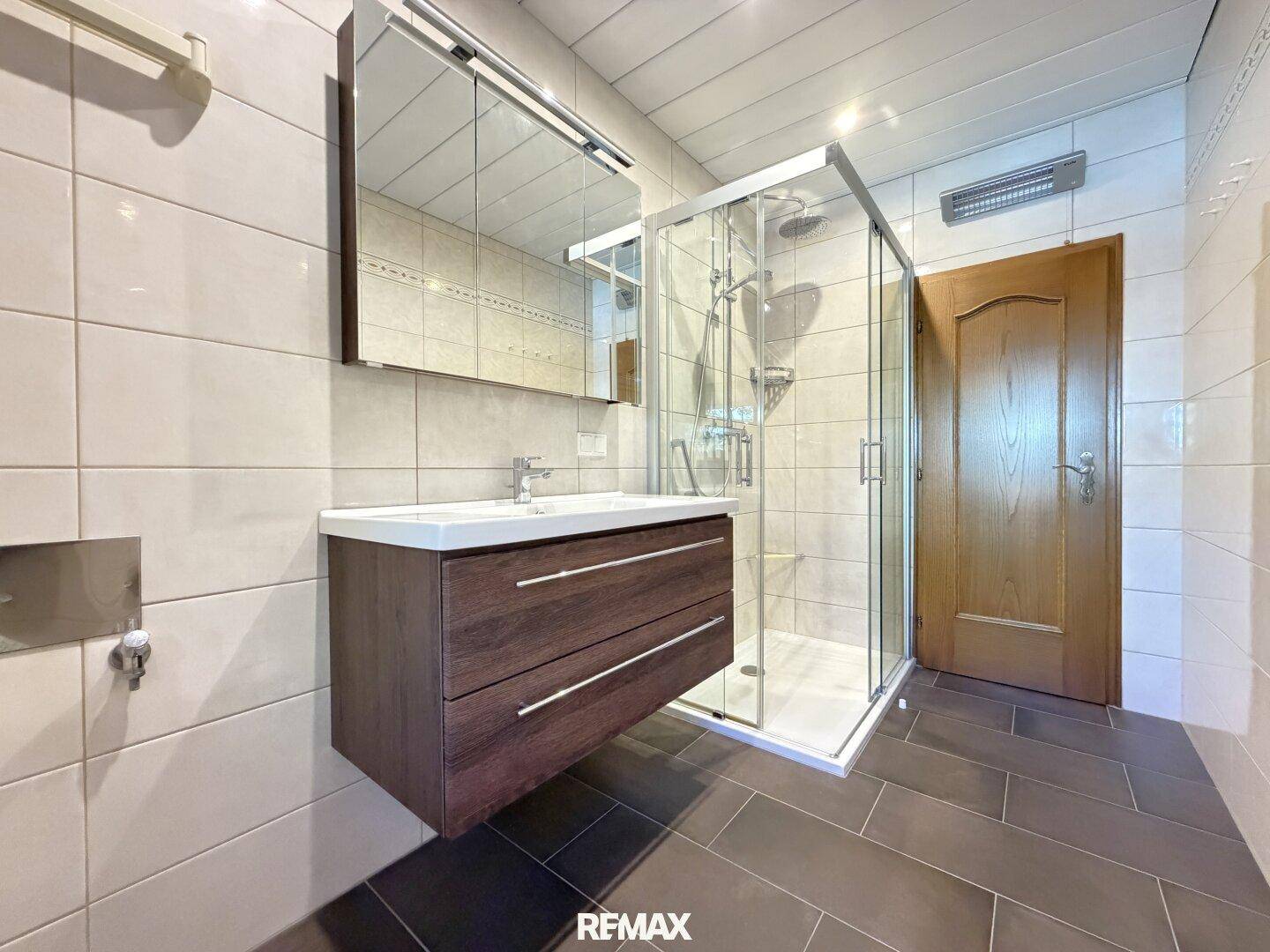 Modernes Badezimmer mit schwebendem Waschtisch, Spiegelschrank und Duschkabine.