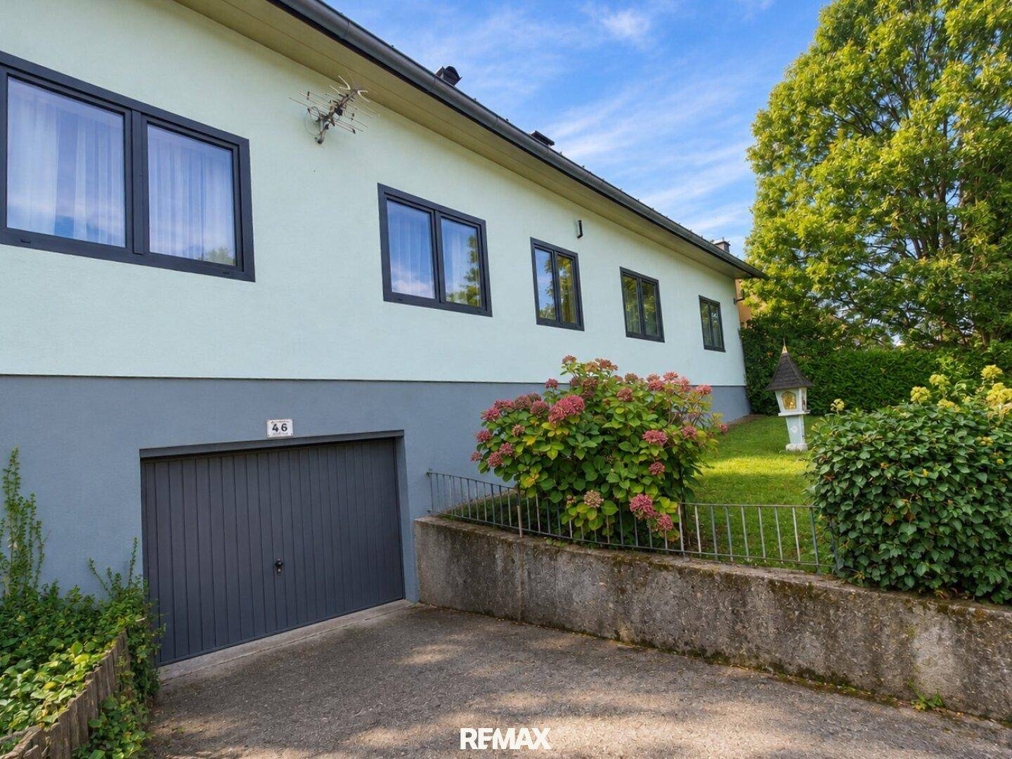 Hausfassade mit integrierter Garage und gepflegten Blumenbeeten im Eingangsbereich.