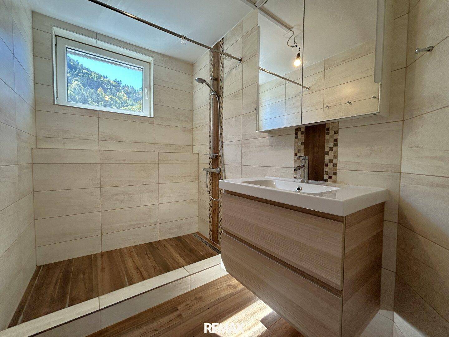 Modernes Badezimmer mit begehbarer Dusche, Holzoptik-Fliesen und Fenster mit Bergblick.