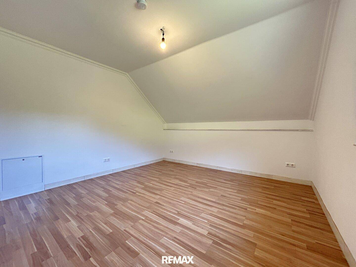 Dachgeschosszimmer mit Laminatboden, weißen Wänden und Dachschräge.