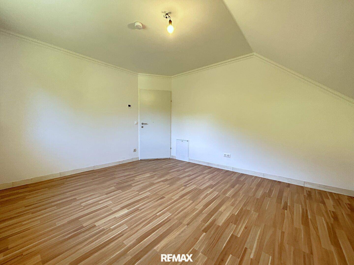 Helles Dachgeschosszimmer mit Laminatboden und weiß gestrichenen Wänden.