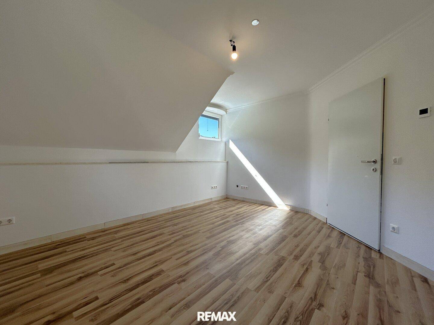 Lichtdurchflutetes Dachgeschosszimmer mit Laminatboden und schräger Decke.