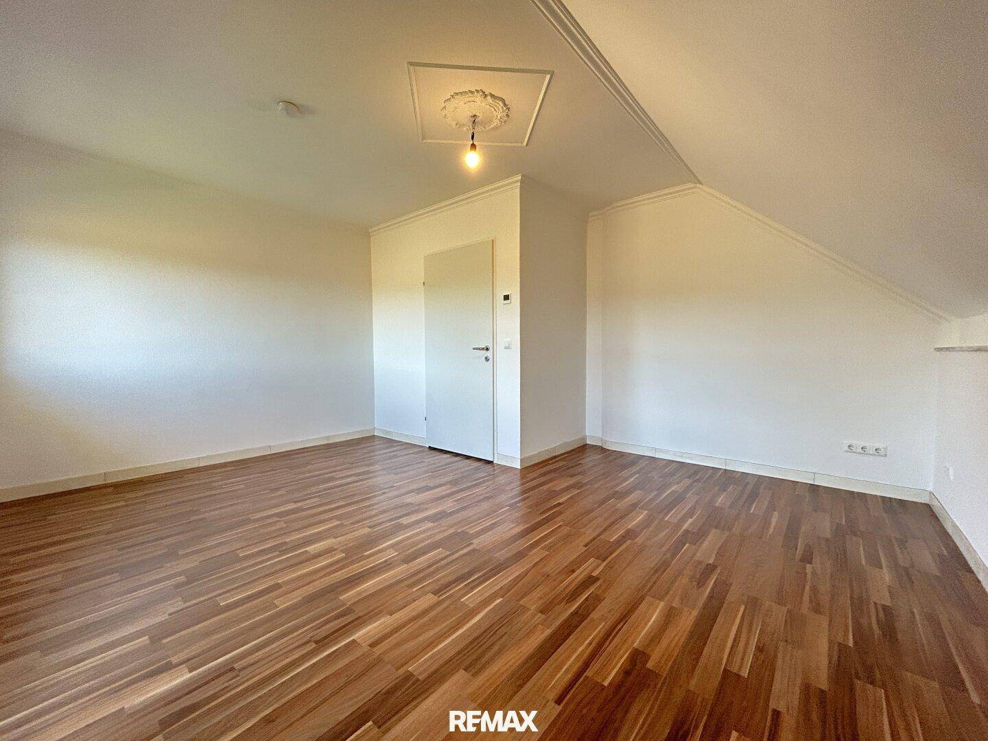 Geräumiges Zimmer im Dachgeschoss mit Holzboden und viel Tageslicht, ideal als Schlafzimmer.
