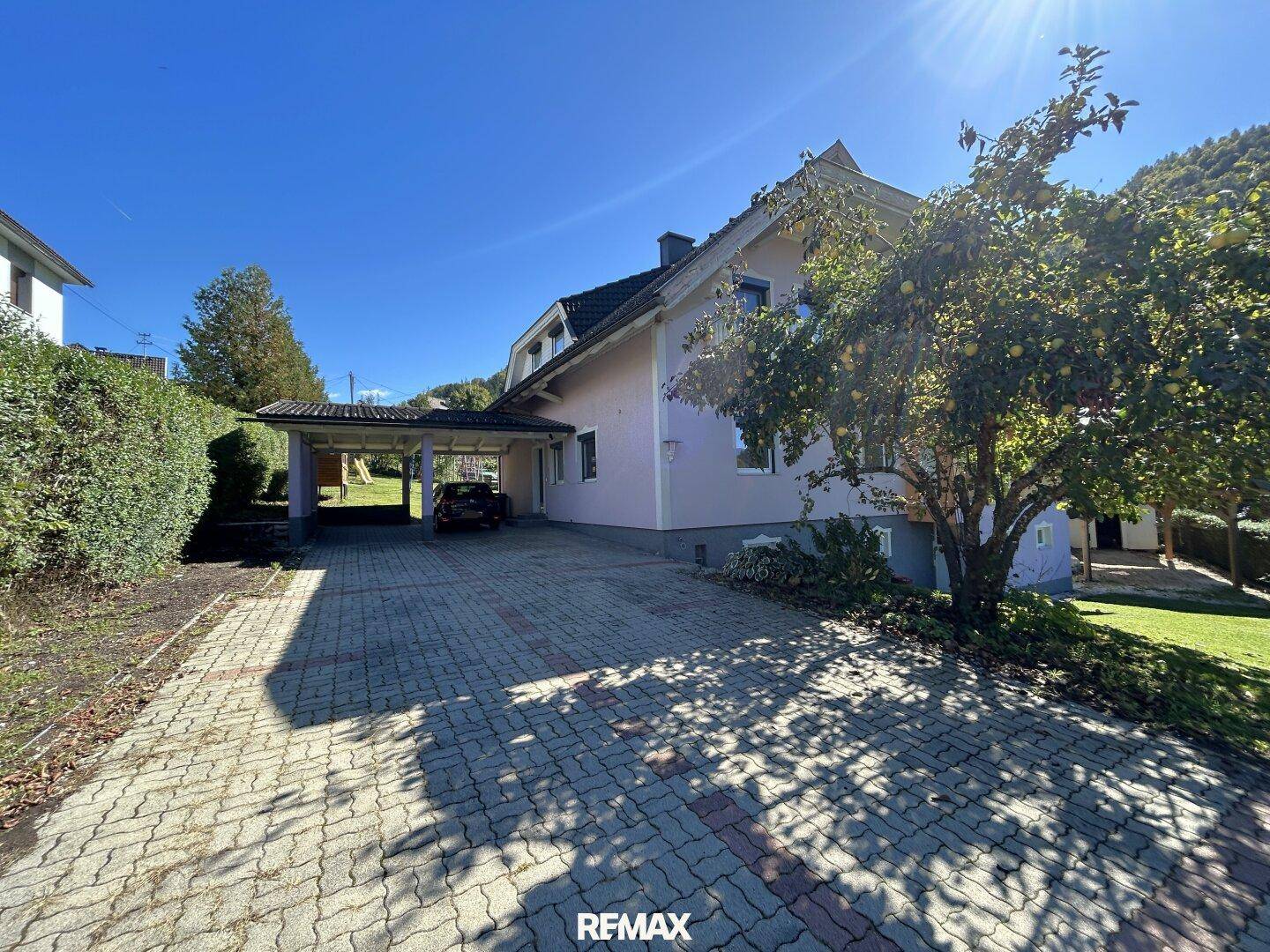 Ansicht des Hauses mit gepflasterter Einfahrt, Carport und einem gepflegten Vorgarten.