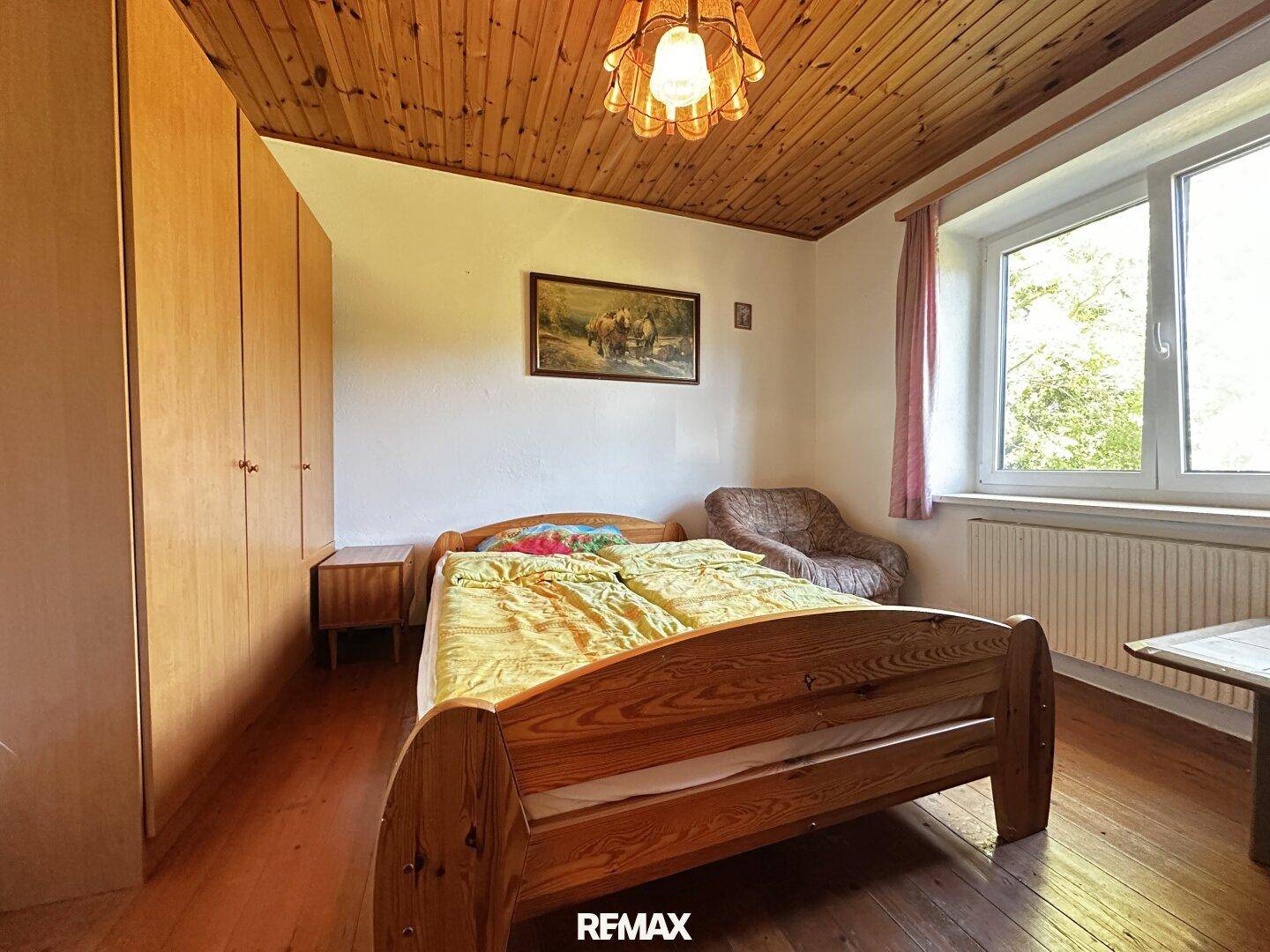 Gemütliches Schlafzimmer mit Holzbett, Kleiderschrank und Holzdecke.