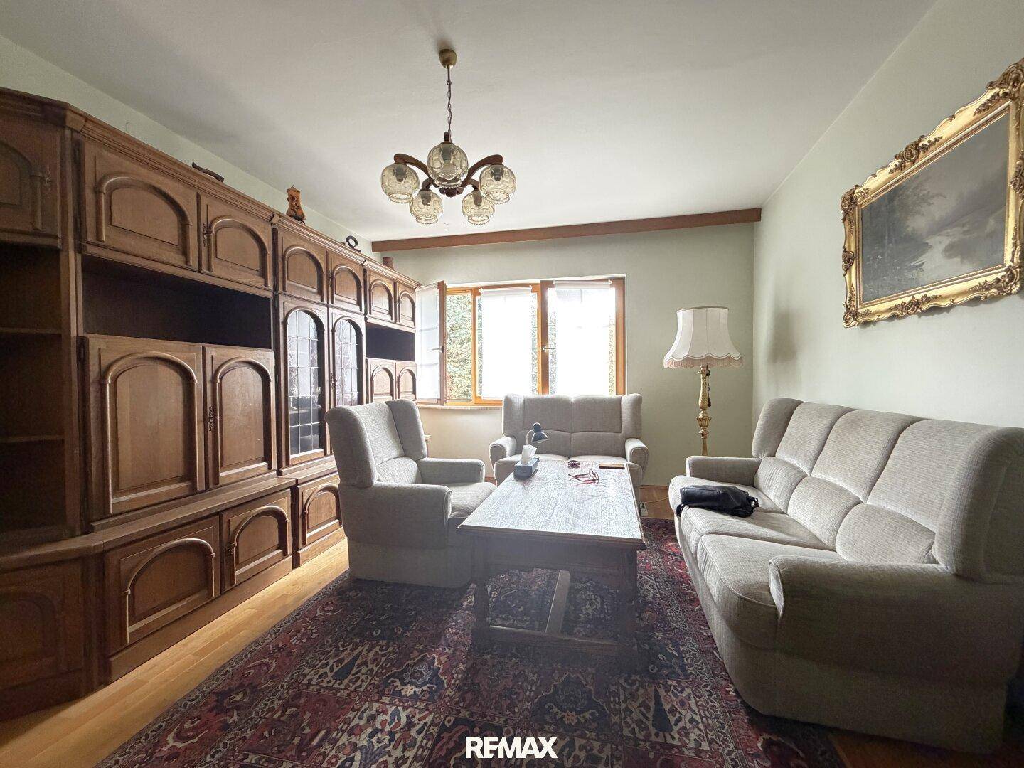 Geräumiges Wohnzimmer mit Holzboden, großem Wandschrank und traditionellen Sitzmöbeln.