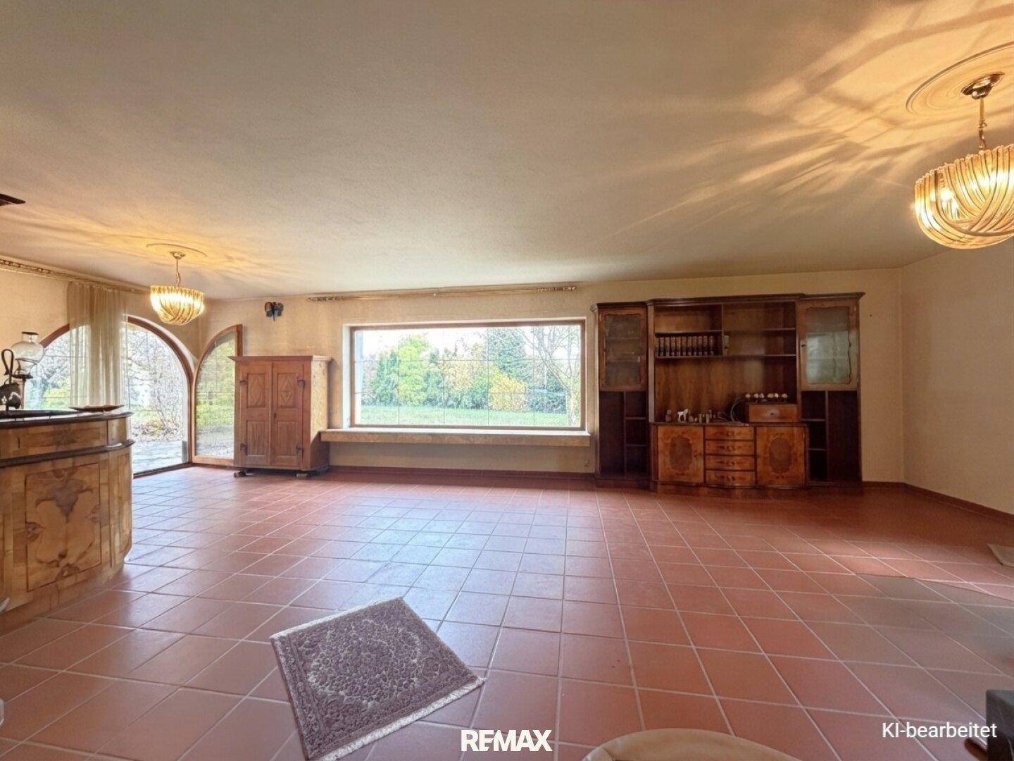 Großzügiges Wohnzimmer mit Terrakotta-Boden, großen Fenstern und traditionellen Holzmöbeln.
