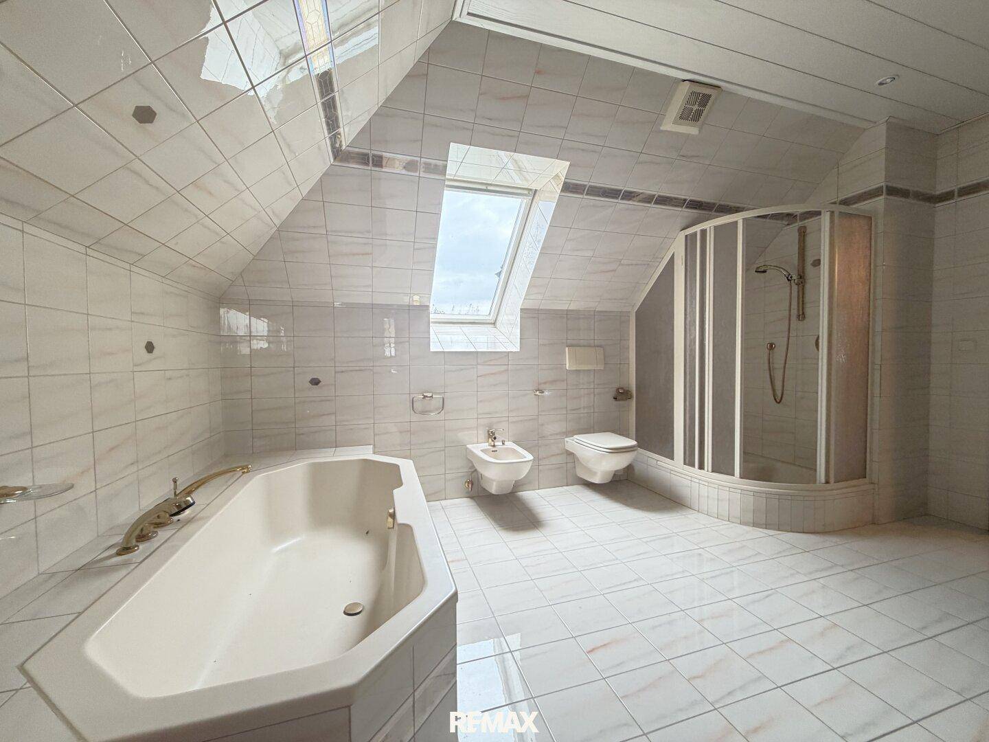 Helles Badezimmer im Dachgeschoss mit Badewanne, Dusche, Bidet und Dachfenster.
