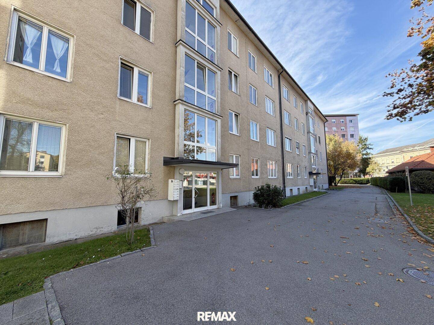 Mehrstöckiges Wohngebäude mit beige verputzter Fassade, vielen Fenstern und einem Eingangsbereich.