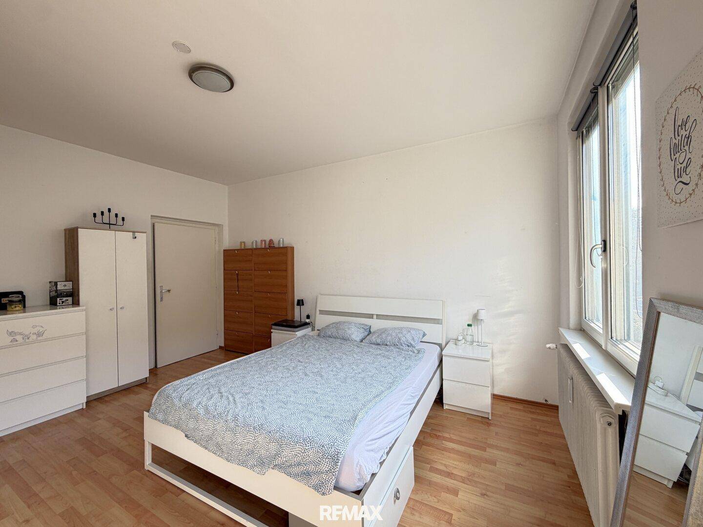 Schlafzimmer mit Doppelbett, Nachttischen und einem Kleiderschrank, ausgestattet mit Holzfußboden.