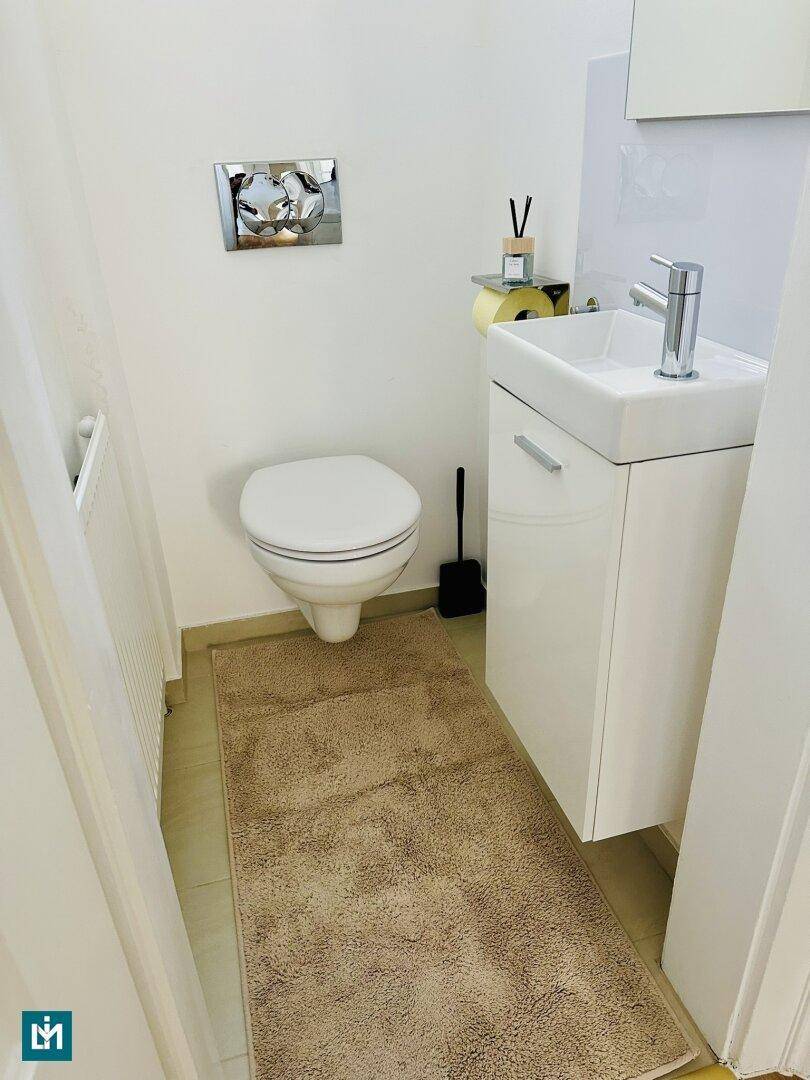 Modernes Gäste-WC mit wandhängender Toilette und kleinem Waschbecken.