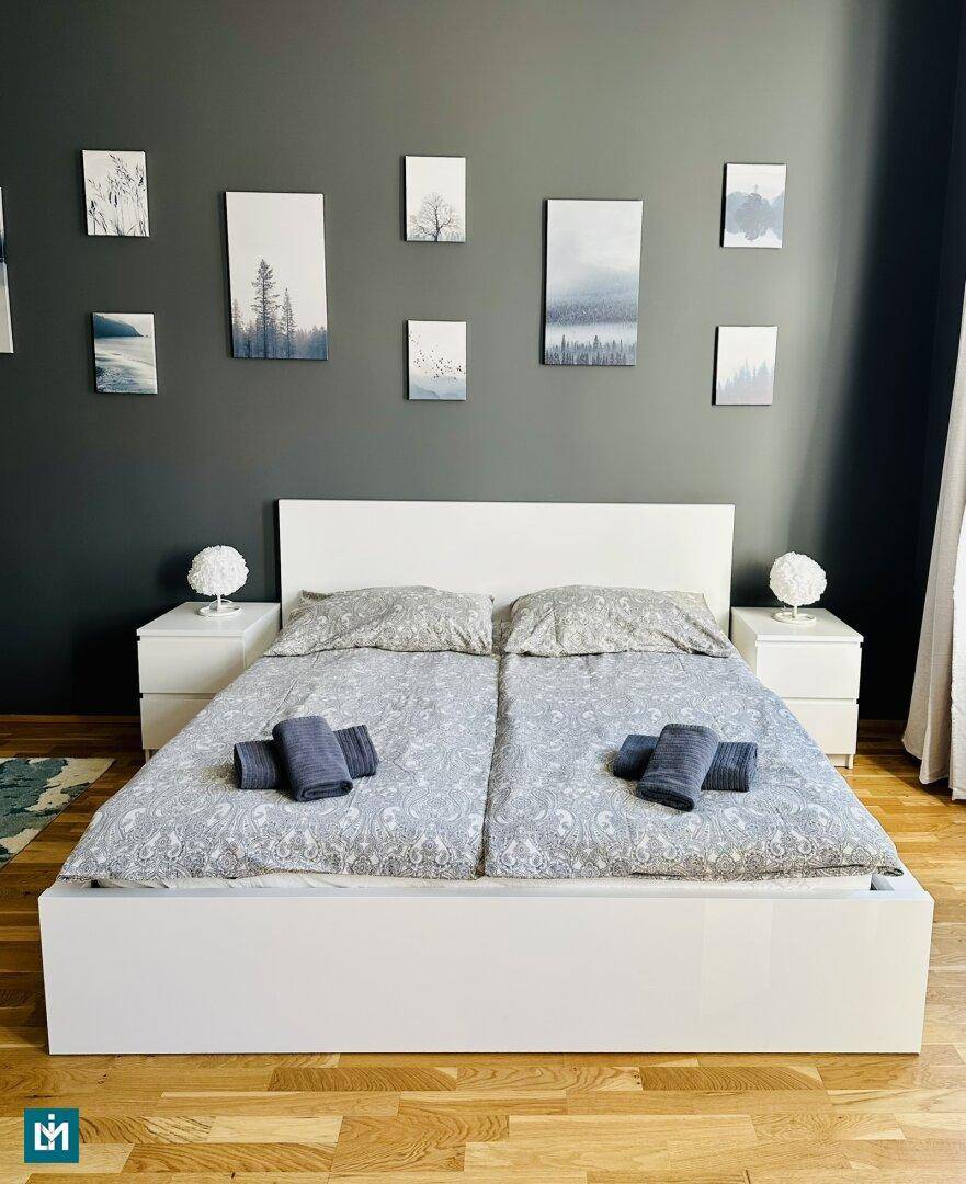 Gemütliches Schlafzimmer mit Doppelbett, Nachttischen und moderner Wanddekoration.