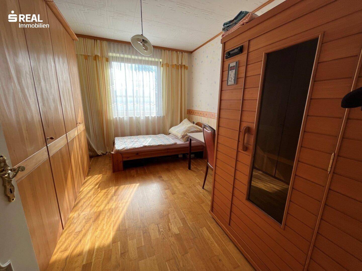 Schlafzimmer mit Einzelbett, großem Holzschrank und einer integrierten Infrarotsaunakabine.