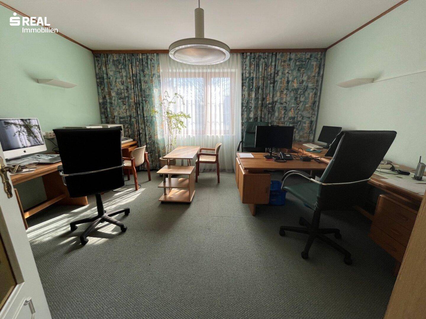 Geräumiges Büro mit mehreren Schreibtischen, Bürostühlen und einem Teppichboden.