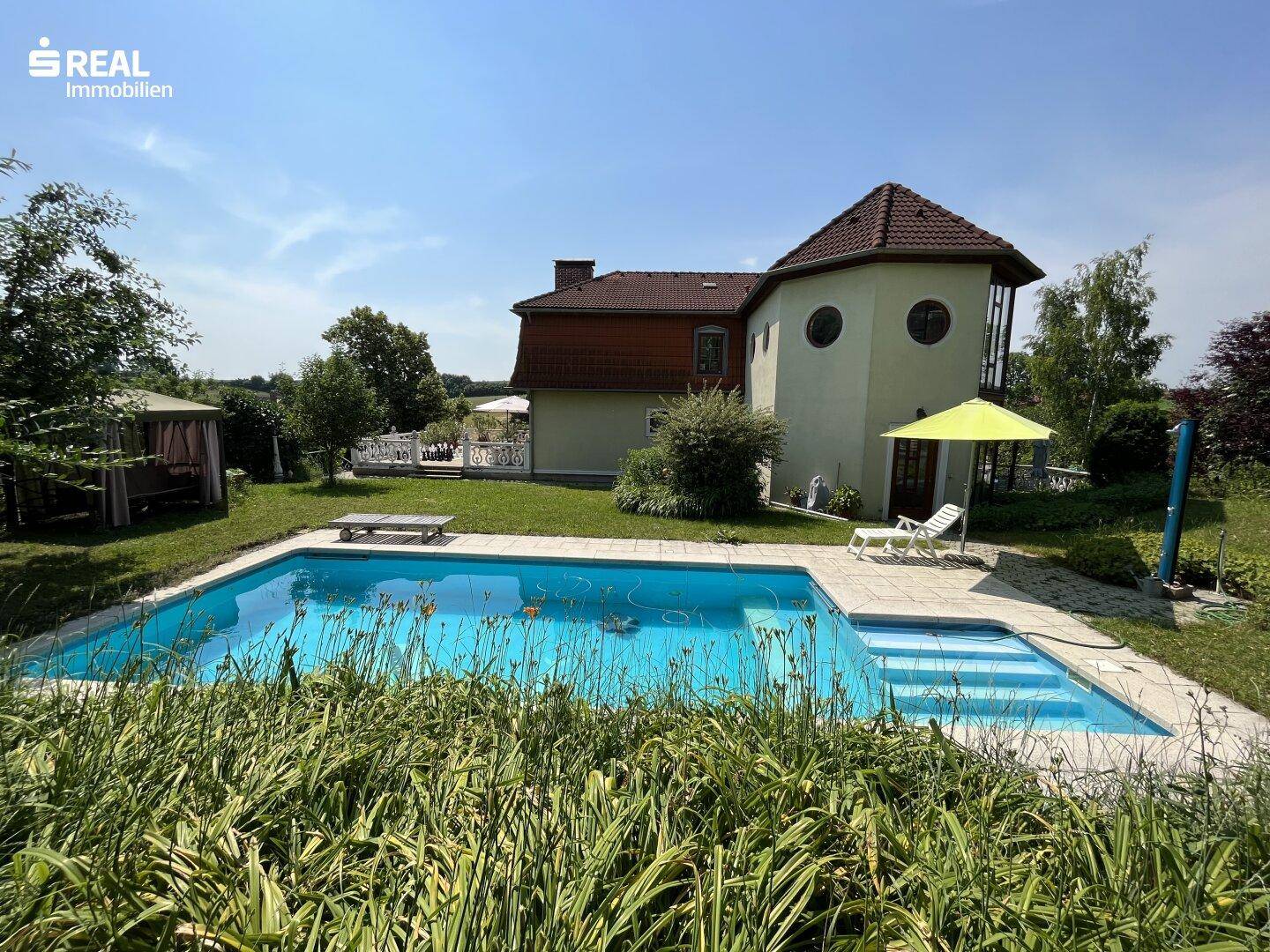 Großzügiger Außenbereich mit Swimmingpool, Liegestühlen und Blick auf das charmante Gebäude.
