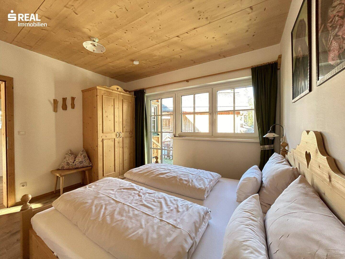 Gemütliches Schlafzimmer mit Holzbett, Holzboden und Blick auf die umliegende Natur.