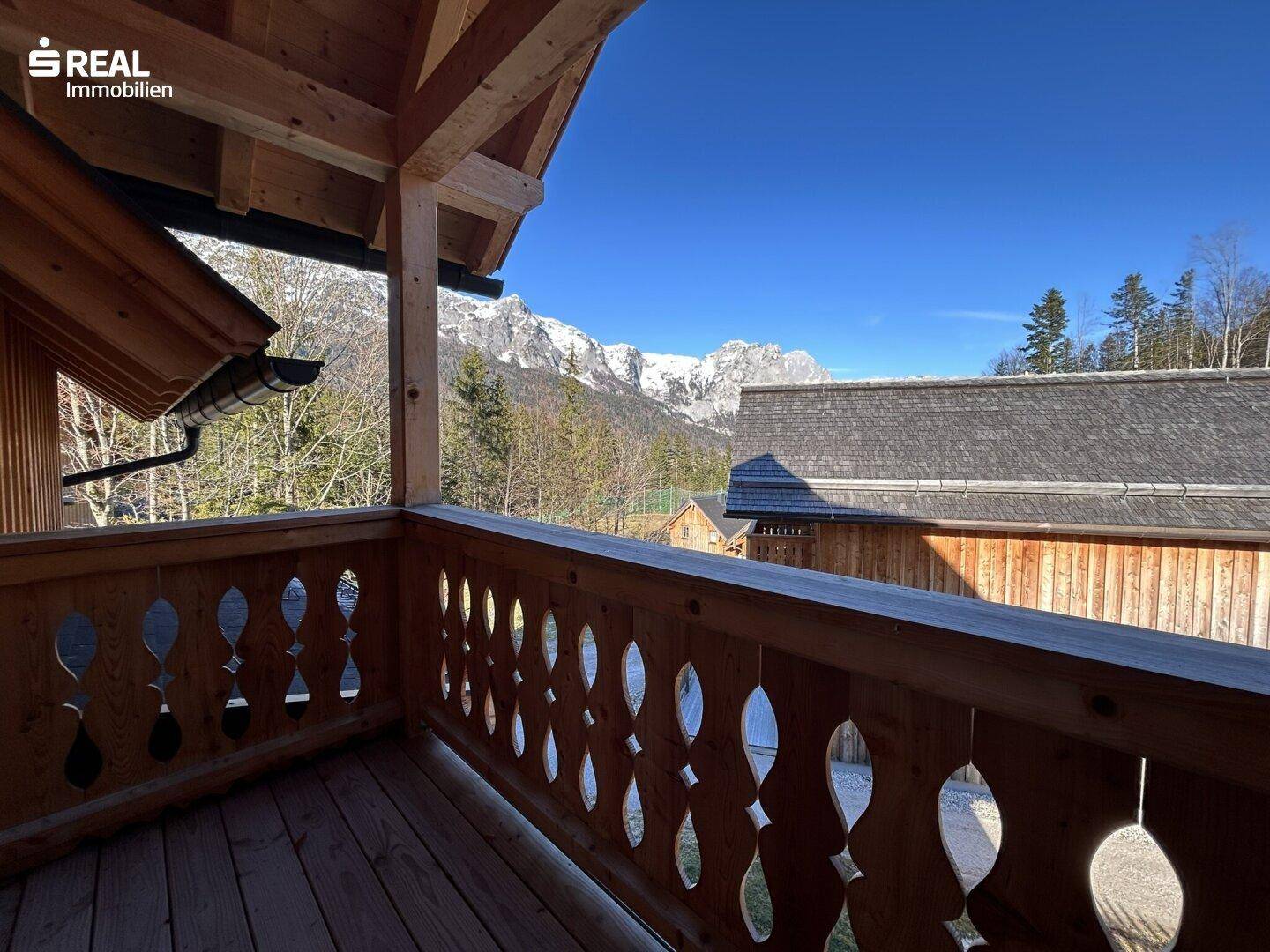 Balkon mit traditionellem Holzgeländer und atemberaubendem Blick auf die schneebedeckten Berge.