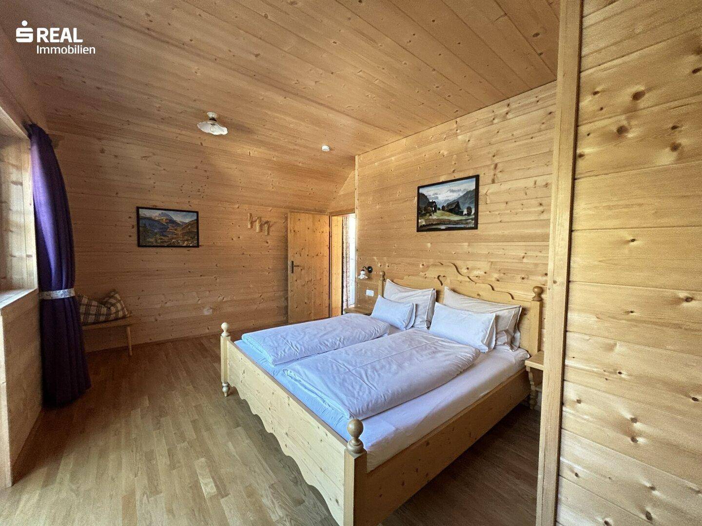 Gemütliches Schlafzimmer im alpinen Stil mit Holzwänden, Holzdecke und einem Doppelbett.