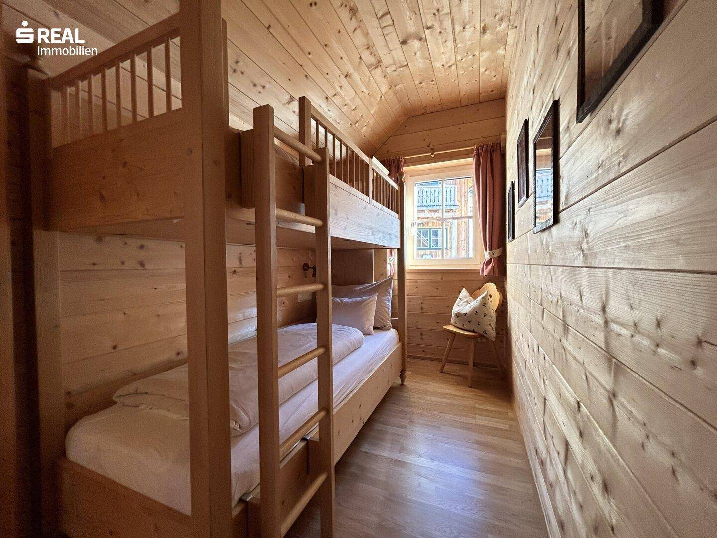 Kinderzimmer oder Gästezimmer mit Etagenbett und Holzwänden im rustikalen Stil.