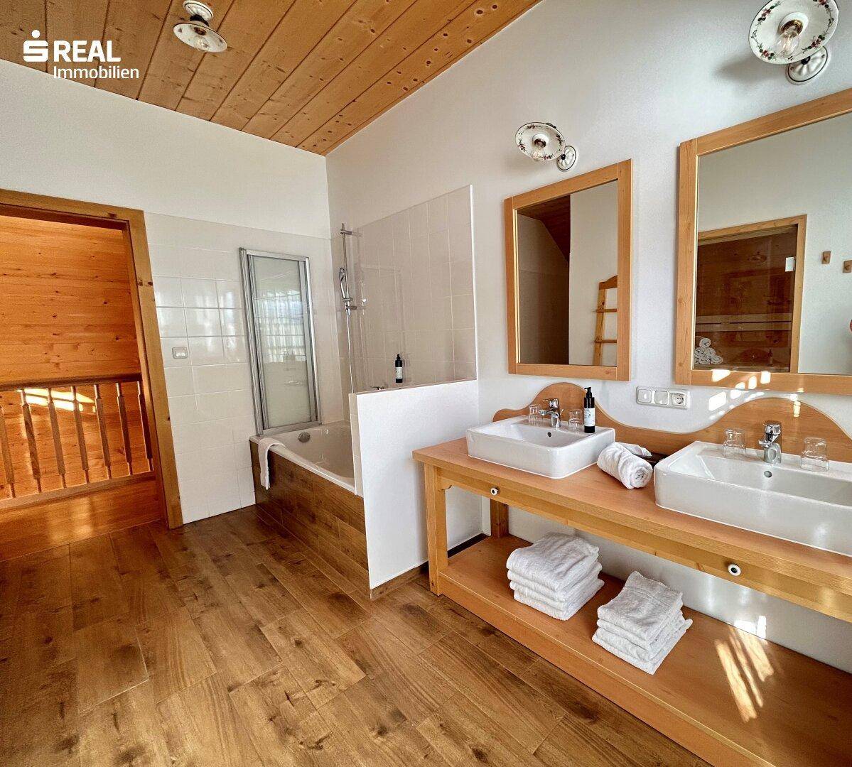 Geräumiges Badezimmer mit Doppelwaschbecken, Badewanne und Holzboden.