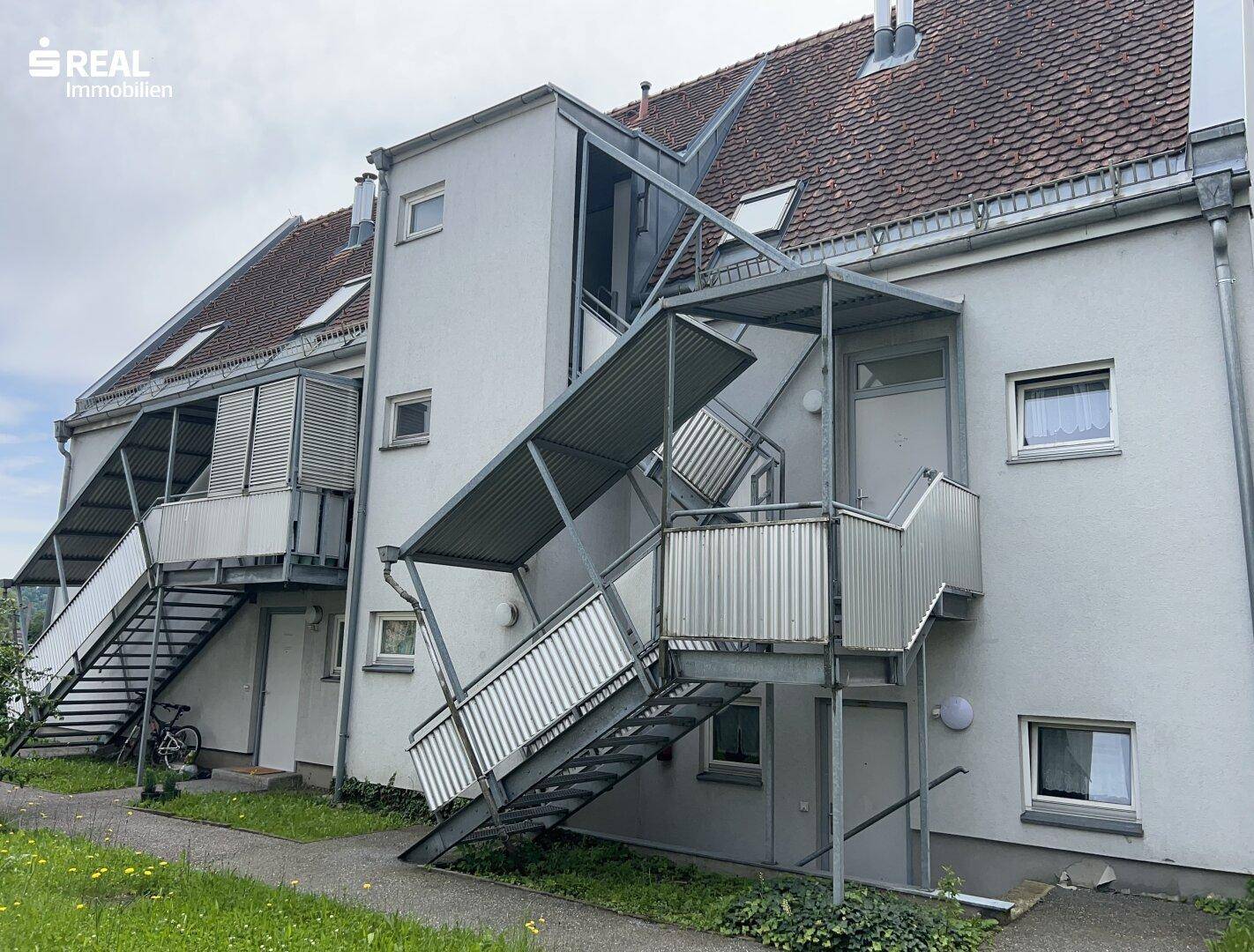 Fassade eines Wohngebäudes mit mehreren Außentreppen, die zu den Eingängen der Wohnungen führen.