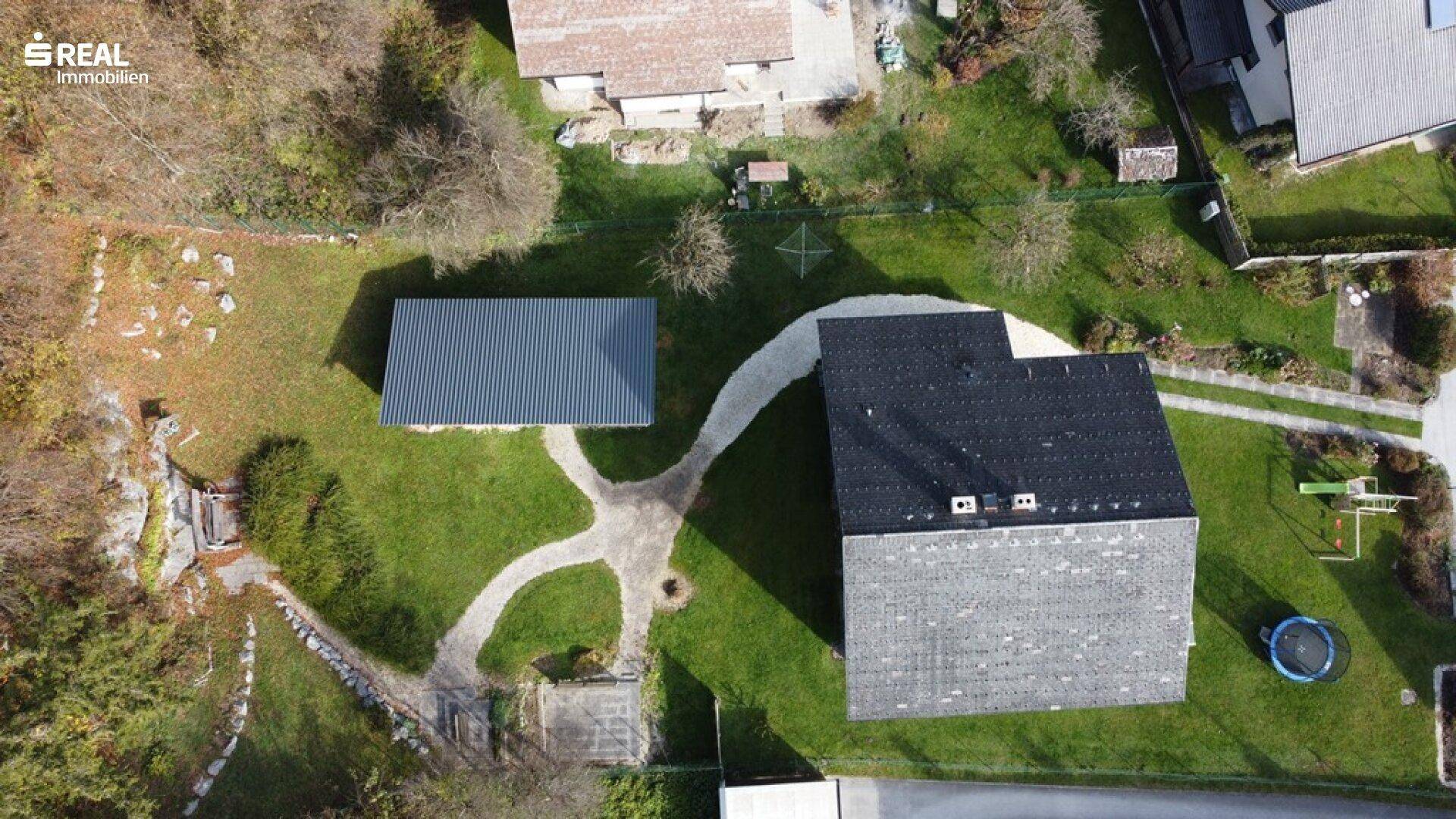 Luftaufnahme des Anwesens mit Hauptgebäude, Nebengebäude und weitläufigen Grünflächen.