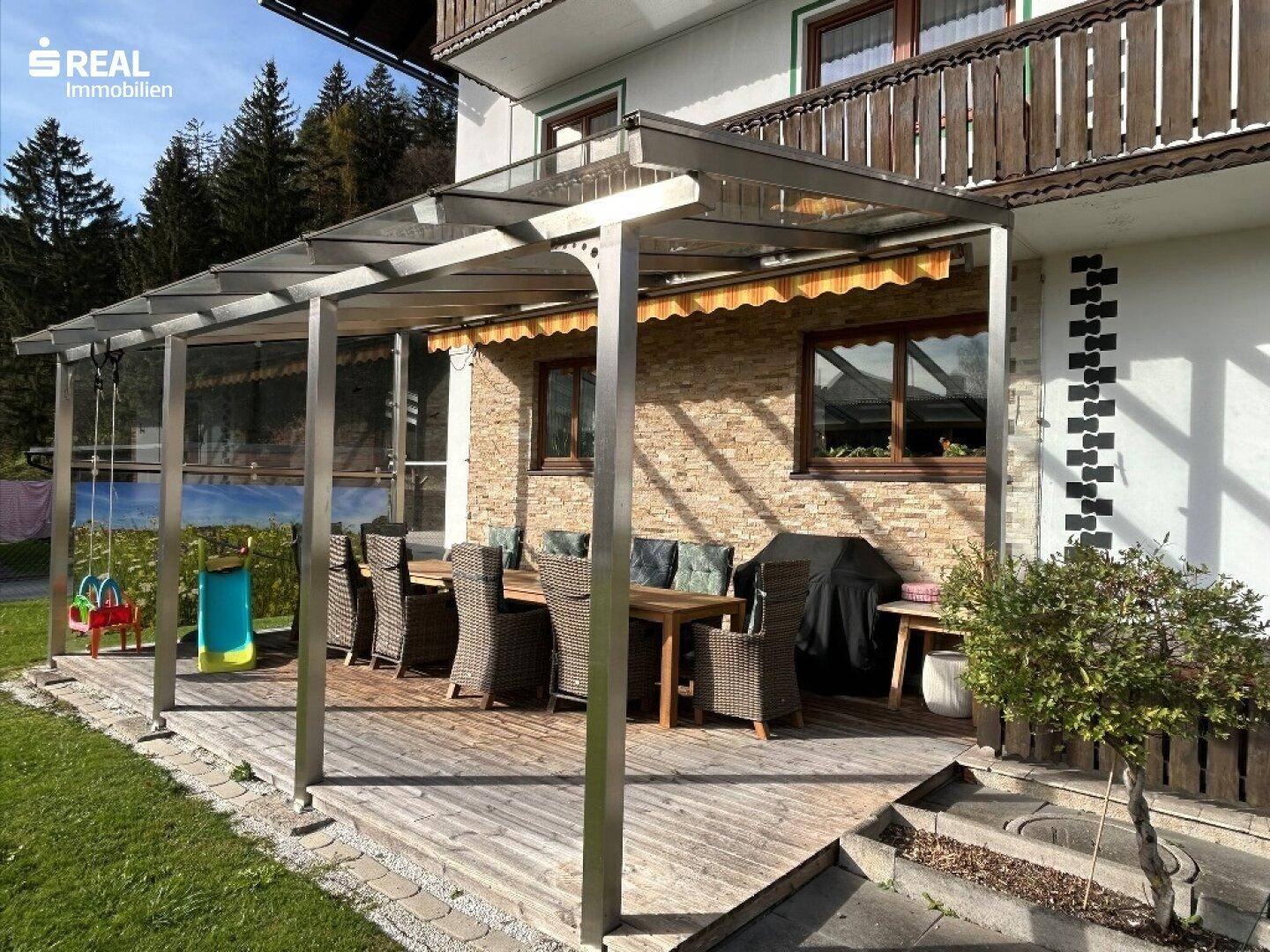 Überdachte Terrasse mit Holzboden und Rattanmöbeln, ideal für Mahlzeiten im Freien.