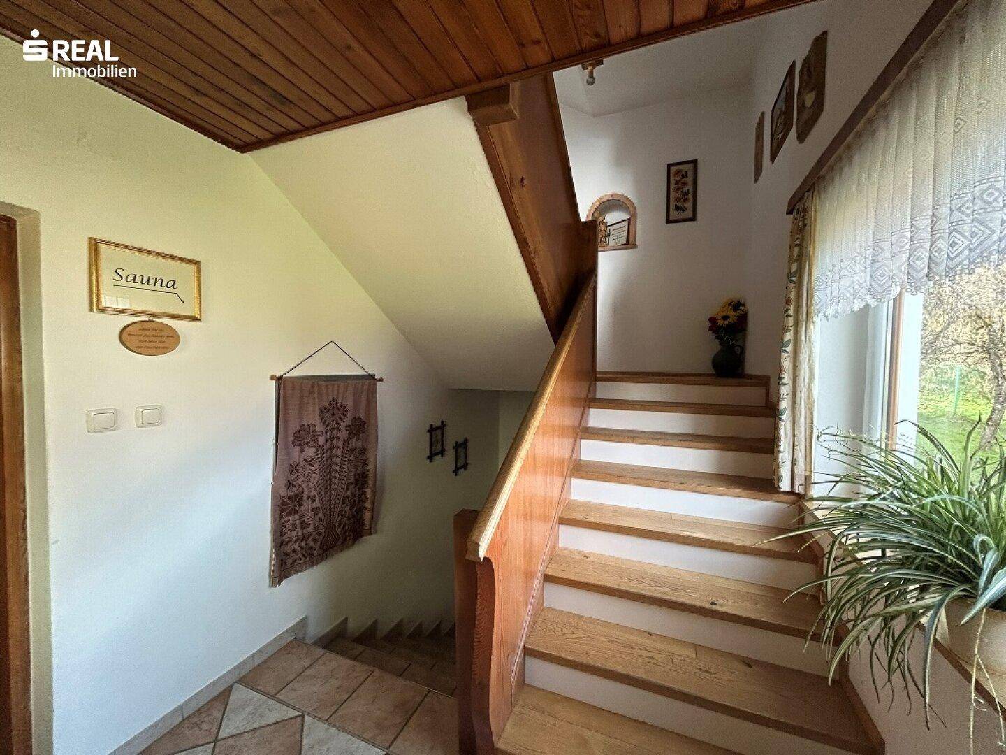 Heller Flur mit Holztreppe und traditionellen Fliesen, führt zu den oberen Etagen.