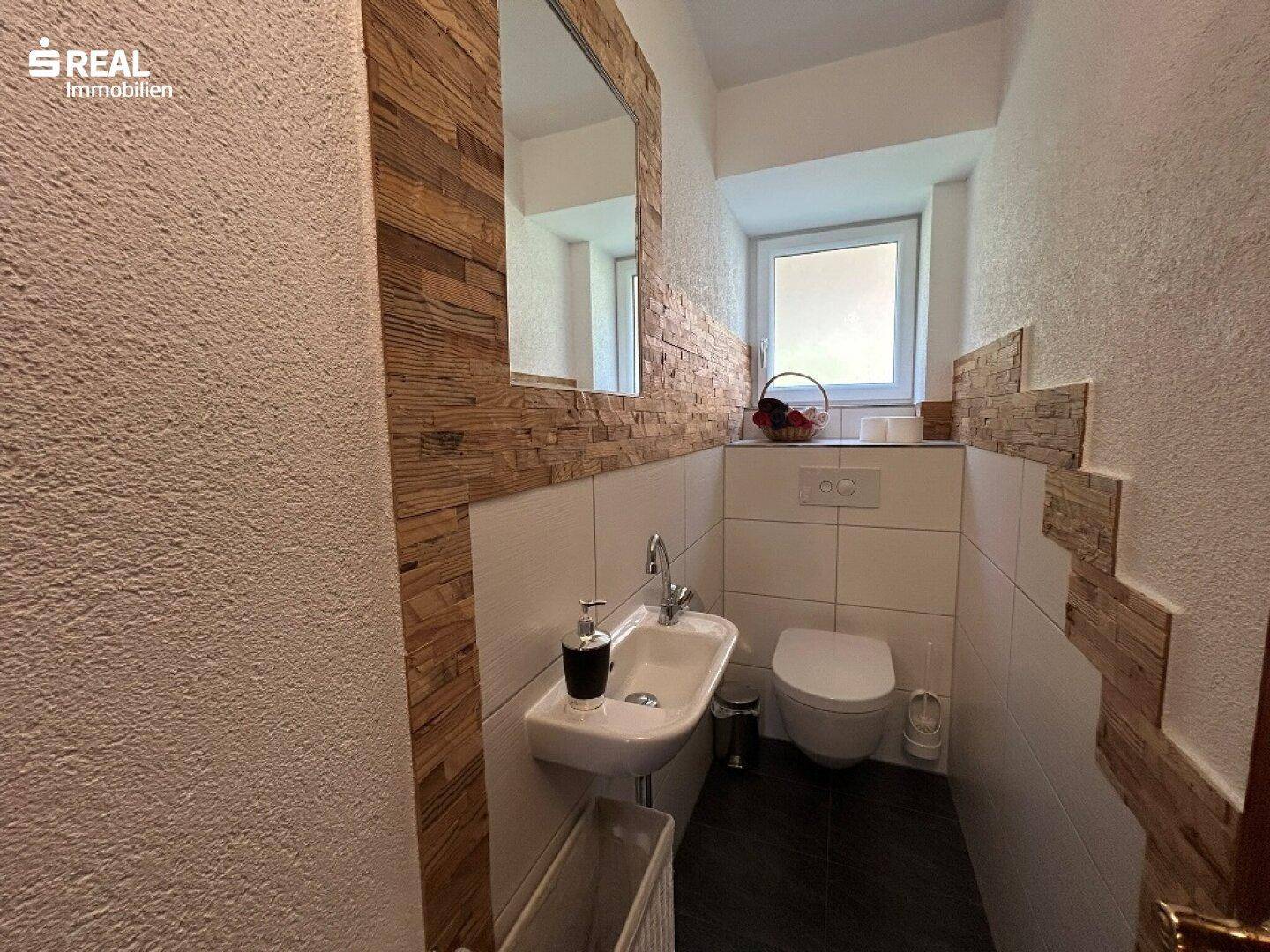 Modernes Gäste-WC mit Wand-WC, Einzelwaschbecken und dekorativer Holzverkleidung.