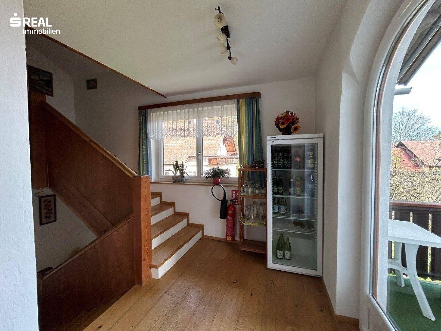Heller Treppenabsatz mit Holzboden und Zugang zu einem Balkon, bietet Tageslicht.