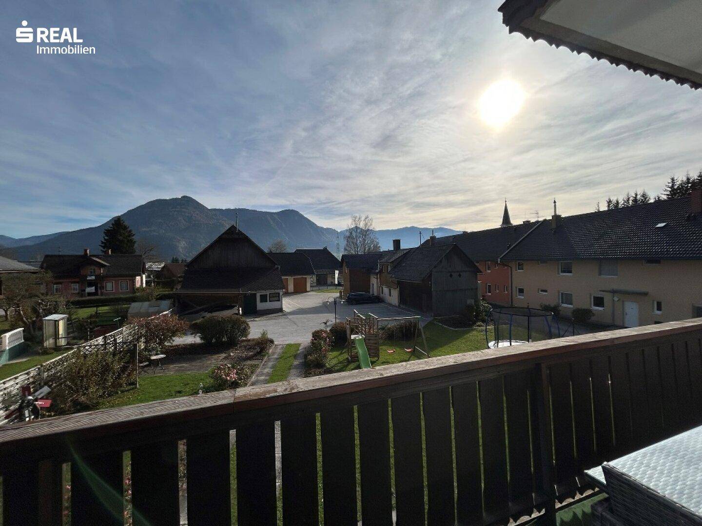 Sonniger Balkon mit Blick auf die Bergwelt und das charmante Dorfleben.